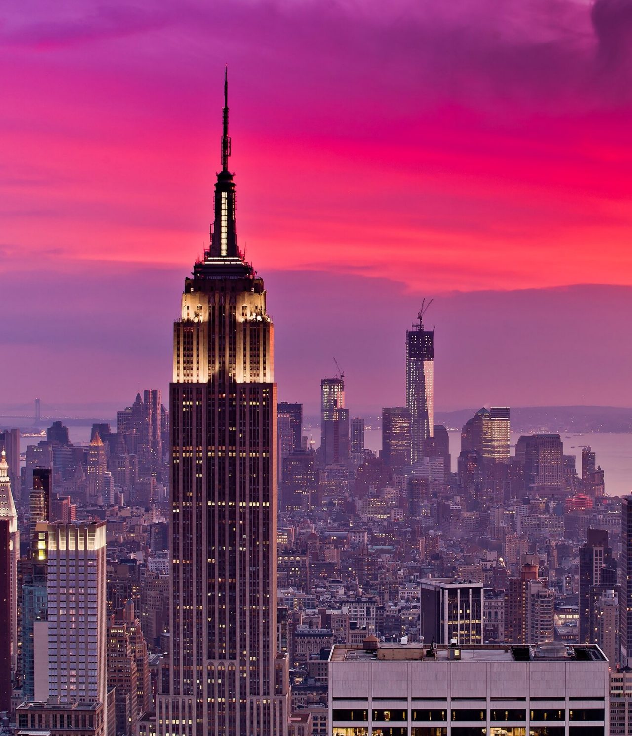 Vista aérea de la ciudad de Nueva York, con el Empire State Building iluminado, rodeado de otros rascacielos y un río