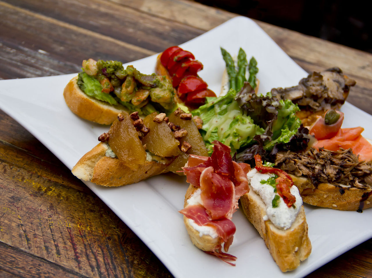 Plato con bocadillos, tapas típicas españolas, con varios rellenos sobre el pan, desde jamón hasta queso y tomate