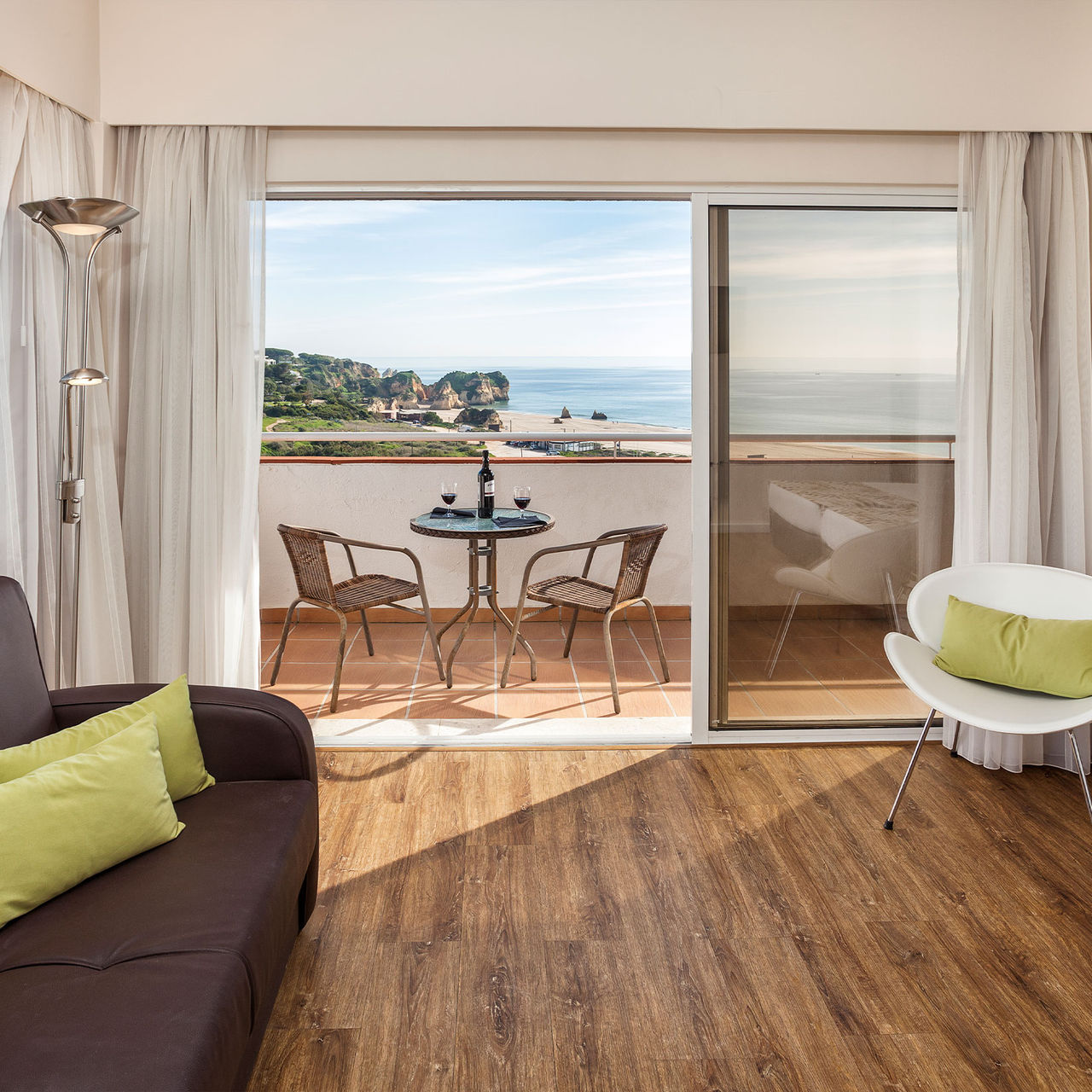 Vista de un apartamento en el Pestana Alvor Atlântico, con un balcón con vista al mar y dos copas de vino