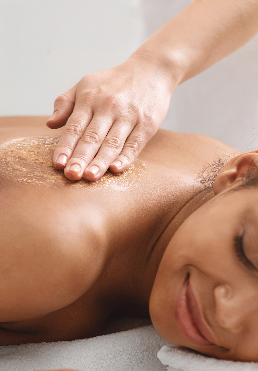 Cliente a receber uma massagem no Pestana Magic Spa, onde o profissional aplica um esfoliante suavemente nas costas