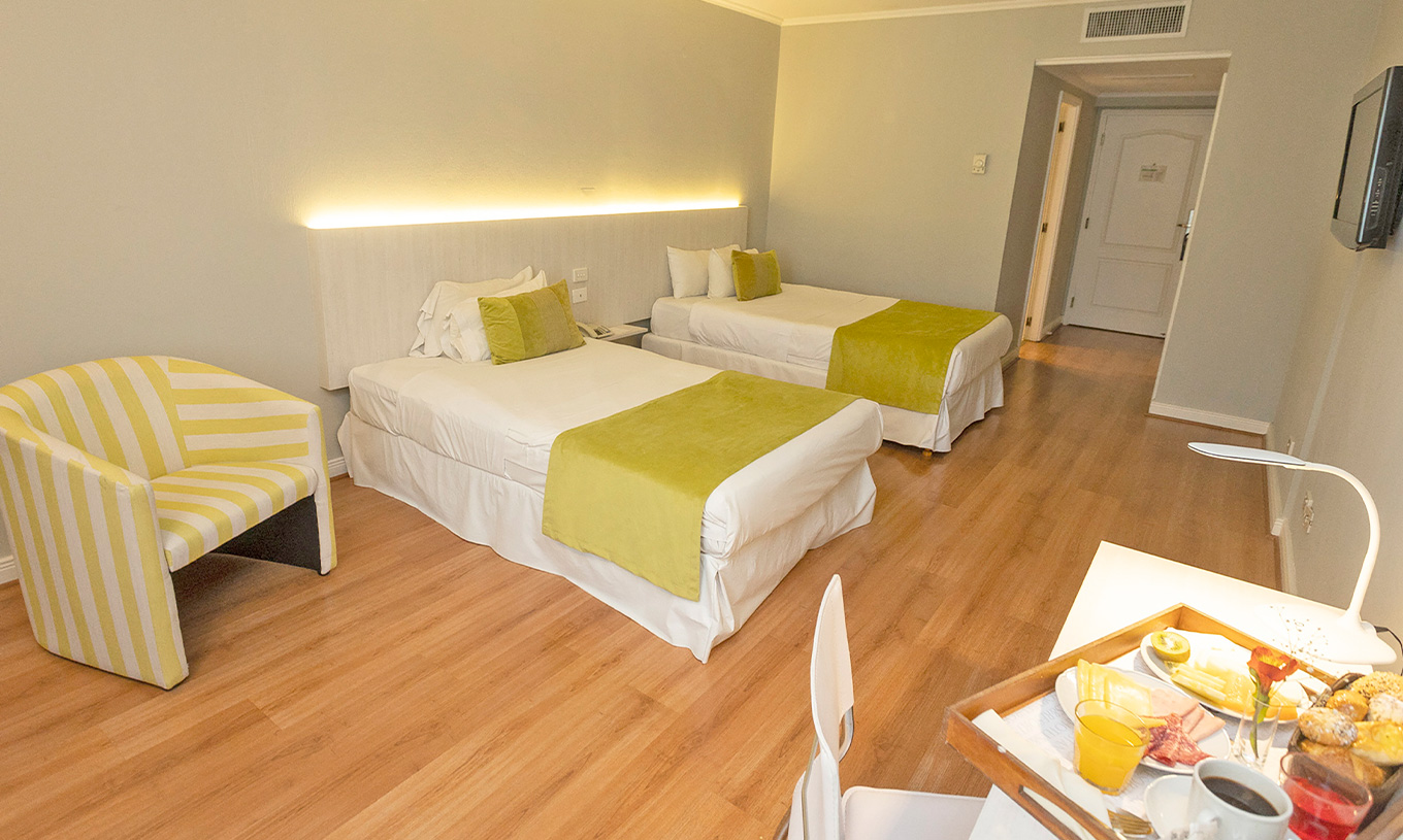 The Twin Standard at Pestana Buenos Aires has two single beds, a bedside table, a chair, and a TV