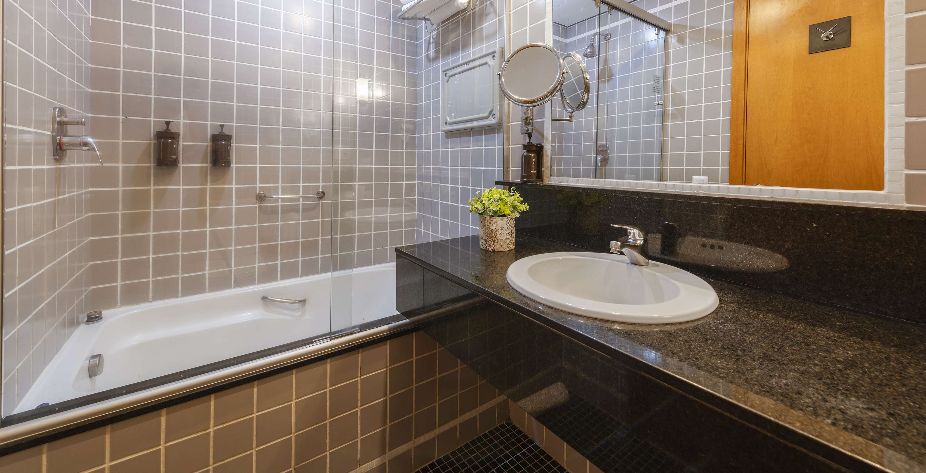 The Twin Standard at Pestana Curitiba has a bathroom with a bathtub in gray tiles and a countertop with a sink