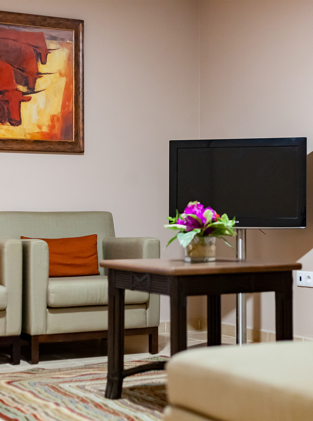 The Junior Suite at Pestana Tropico features two armchairs, a coffee table, and a television