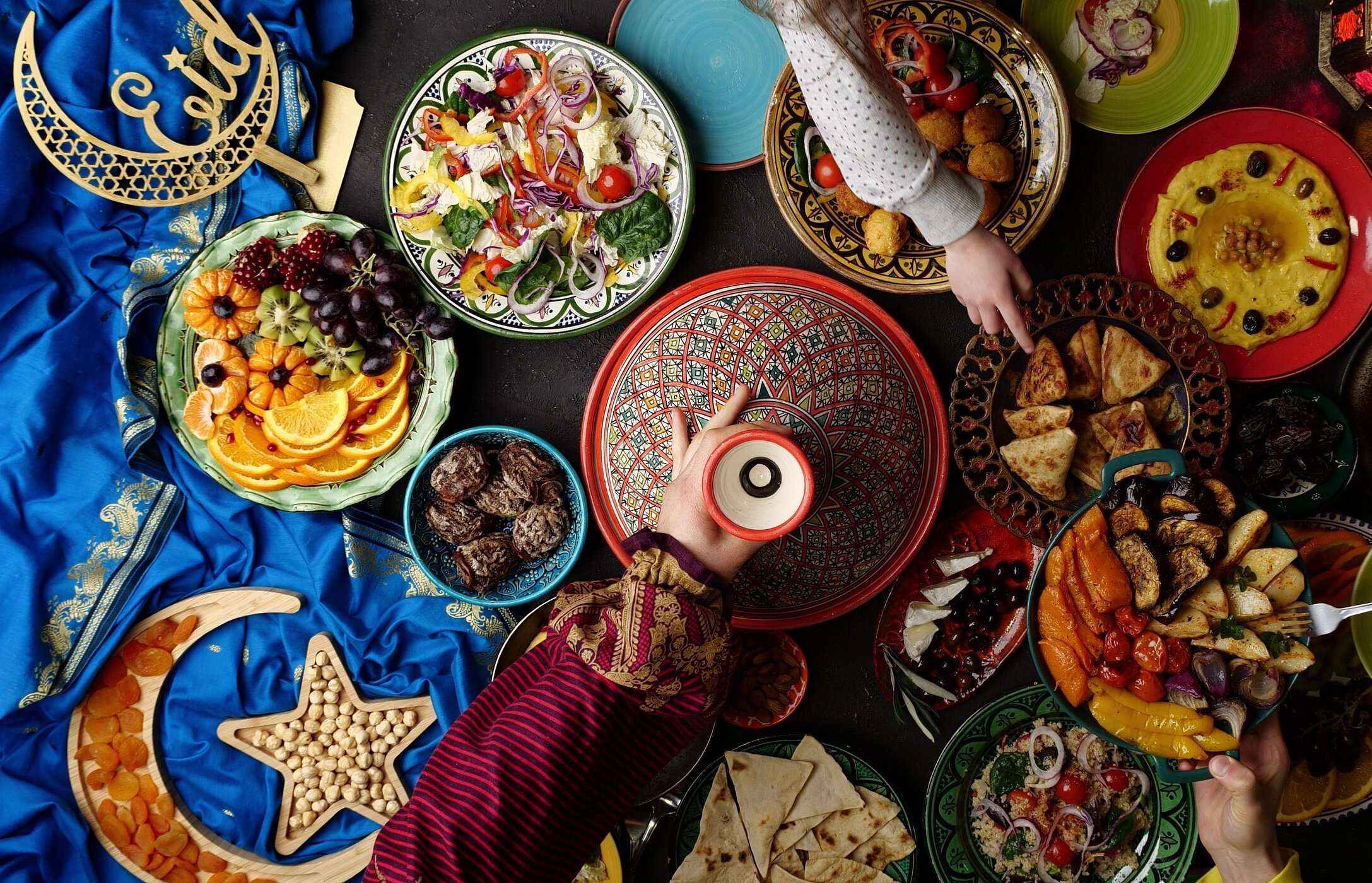 Table with various typical Moroccan dishes, from fruit, salad, dried fruits, to vegetables.