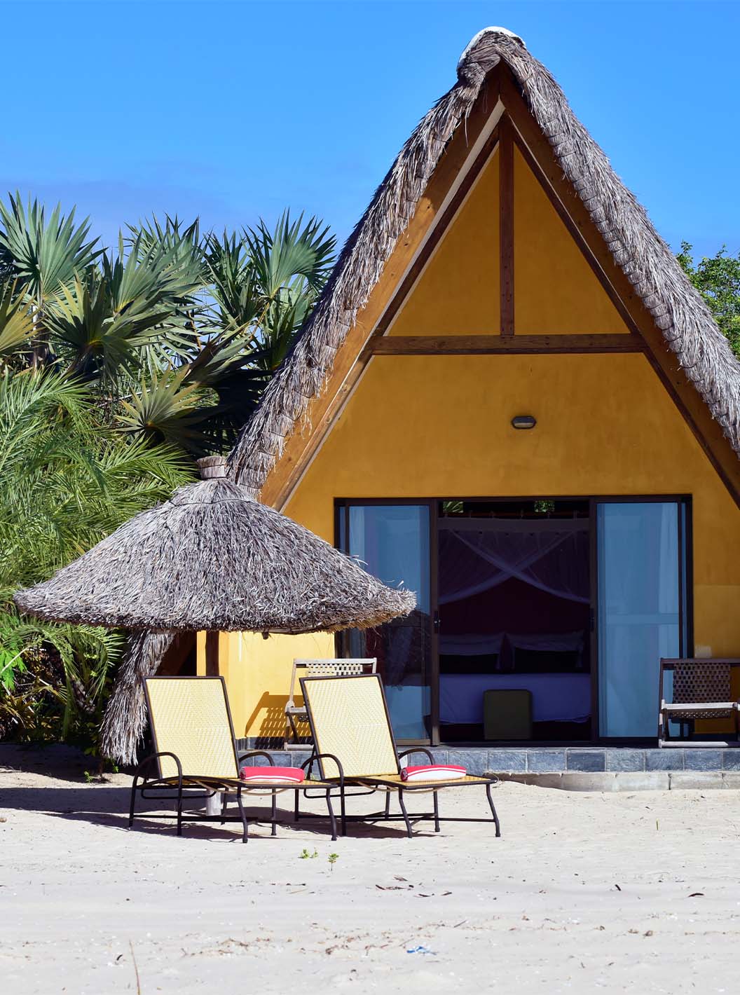 Bungalow T1 at Pestana Bazaruto Lodge is a yellow house on the beach with a thatched roof and A-shape