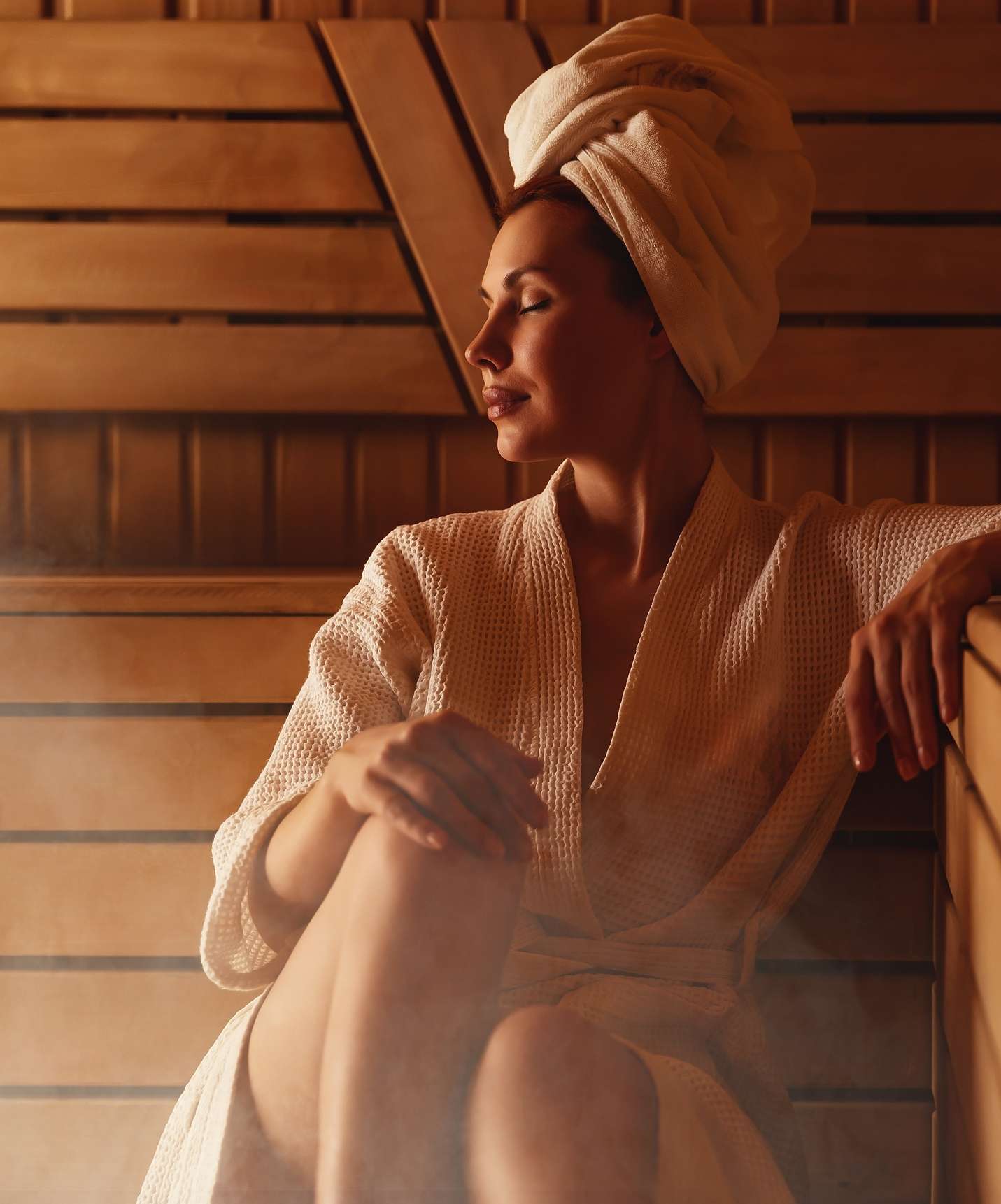 Woman relaxing in the sauna at Pestana Tróia Eco Resort, resort near Comporta, in a bathrobe with a towel on her head