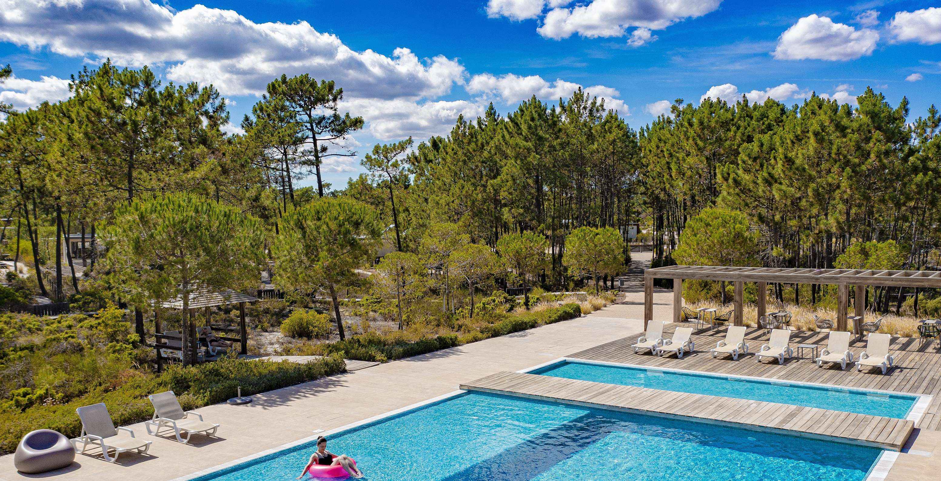 Outdoor pool at Pestana Tróia Eco Resort, with a woman relaxing on a pink float in the pool
