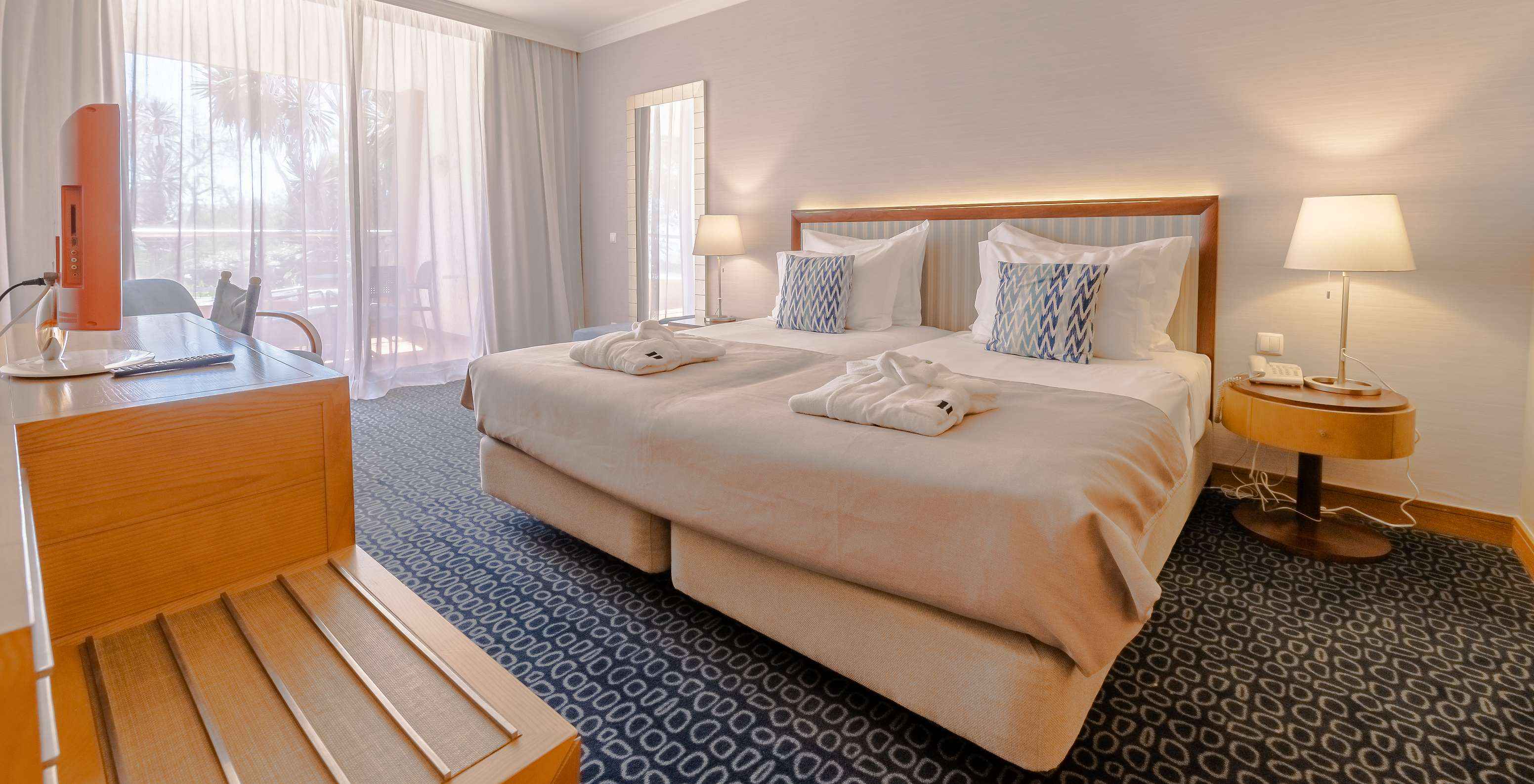 The T1 - with 1 Bedroom at Pestana Alvor Park has a double bed, blue carpet, and a desk with a television