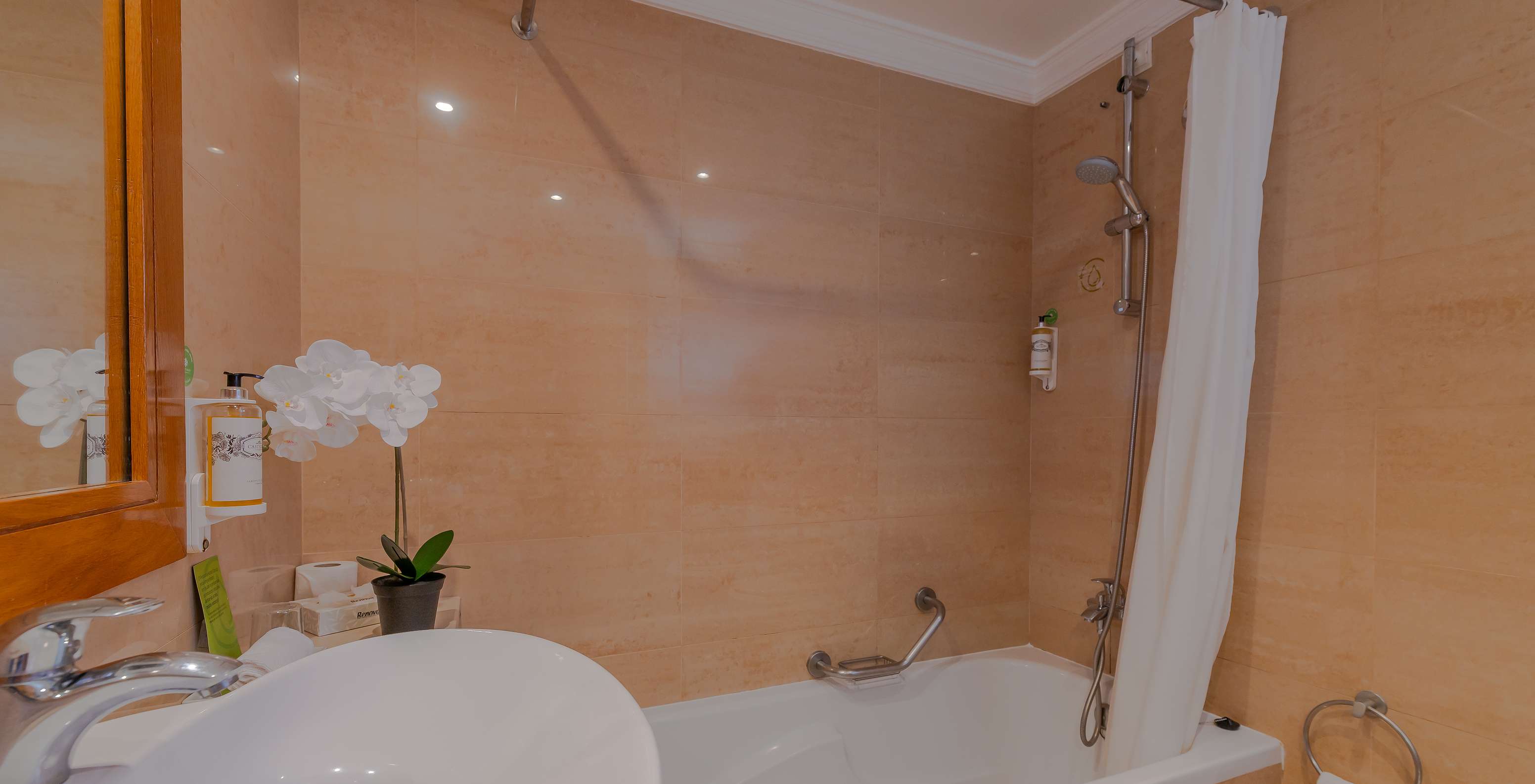 The T0 - Studio at Pestana Alvor Park has a bathroom with a bathtub with a curtain, a sink, and a flower