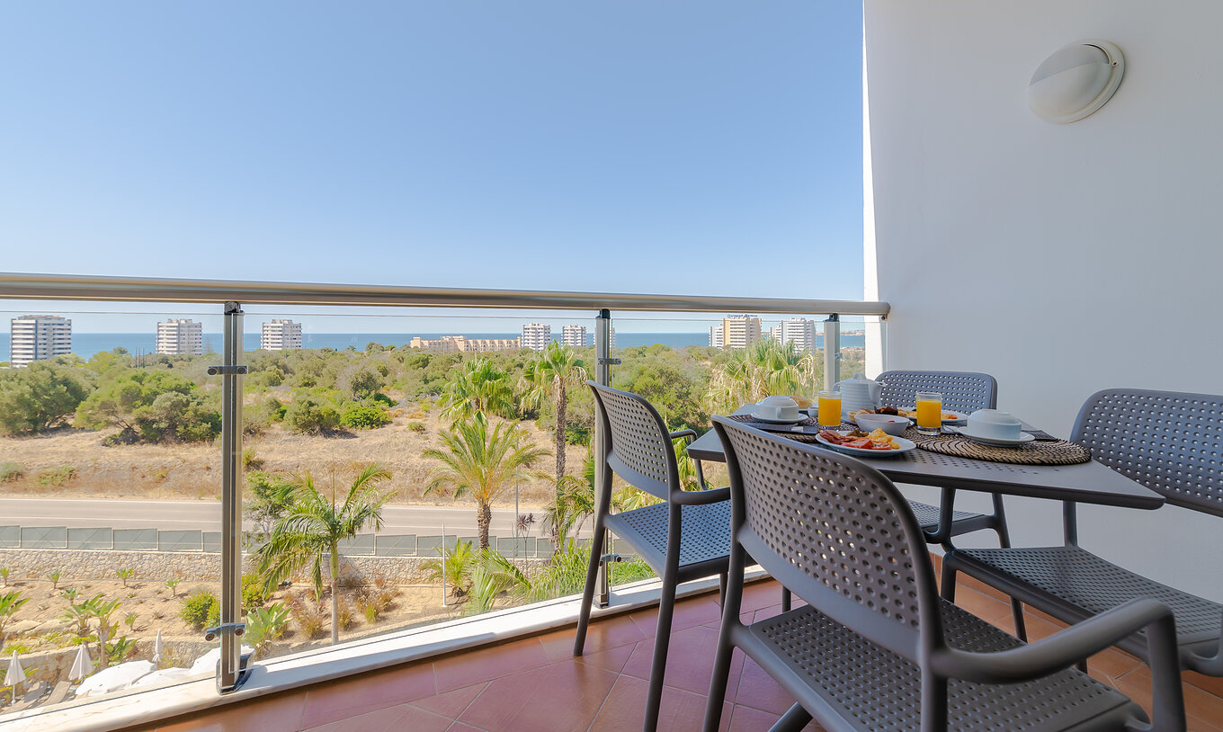 The T1 - with 1 Superior Bedroom at Pestana Alvor Park has a balcony with a table and chairs overlooking the sea
