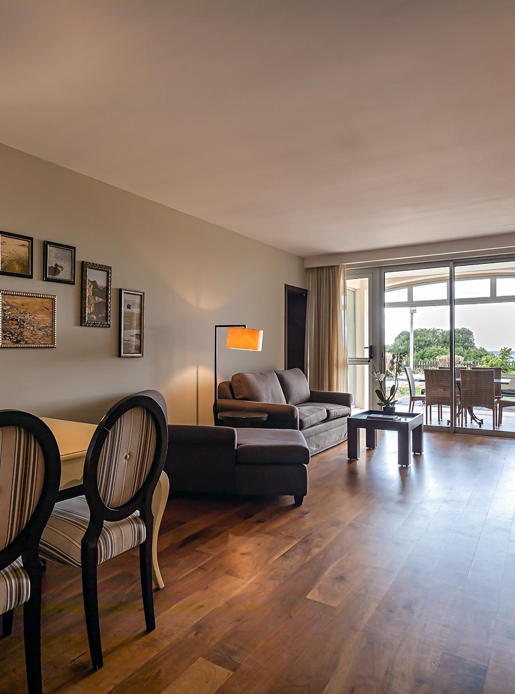 The Cliff Suite T2 at Pestana Alvor Praia has a living room with two sofas, a television, a dining table, and a porch