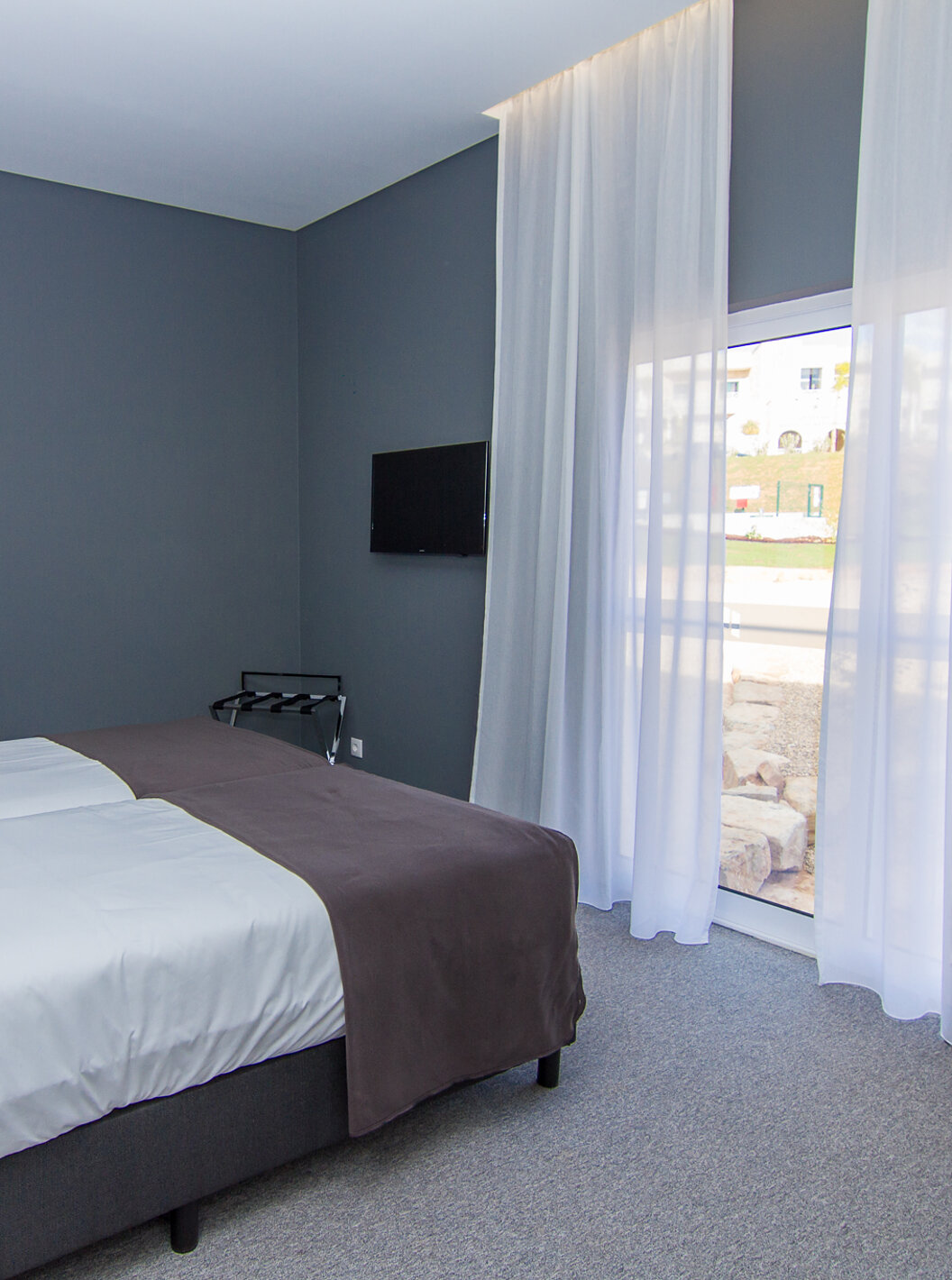 The Classic room at Pestana Gramacho Residences features two single beds, a television, and a window with curtains