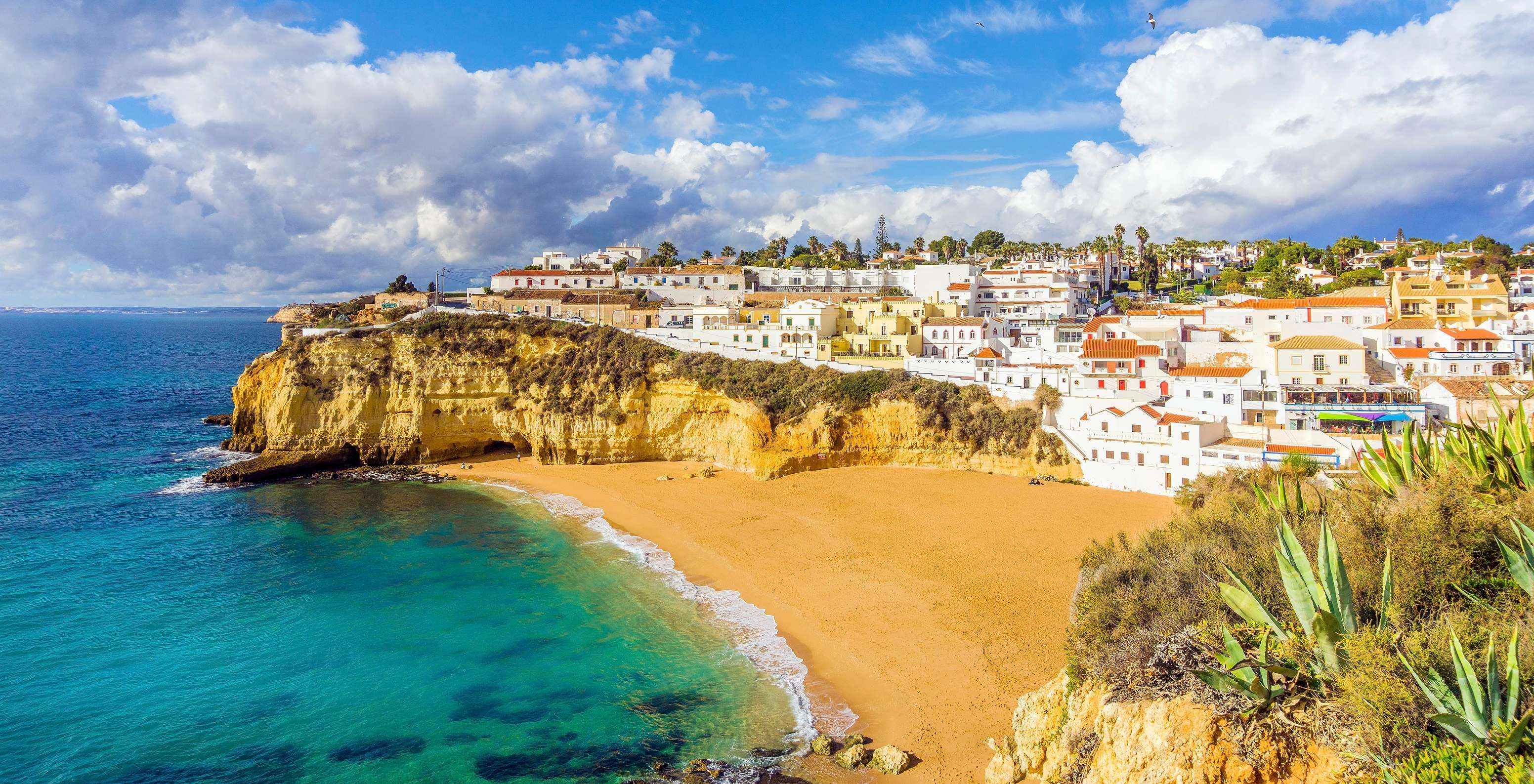 Carvoeiro beach with blue water, Algarve cliffs, and Carvoeiro village in the background