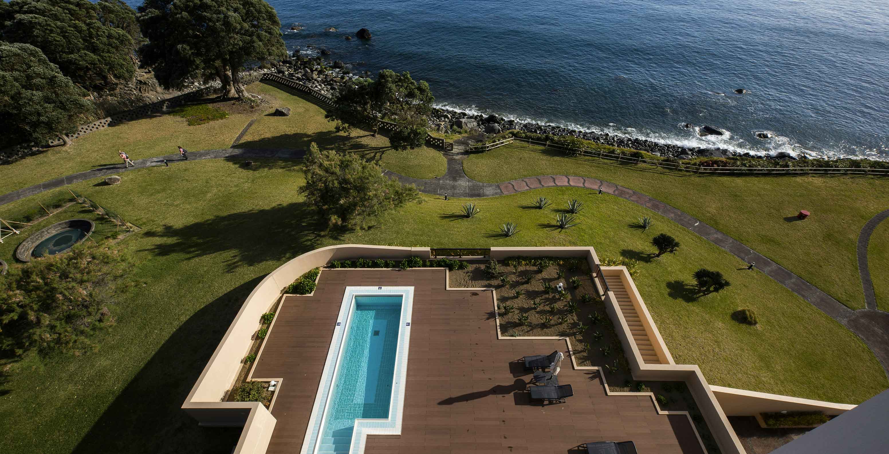Pool at Pestana Bahia Praia on wooden deck with sea view and surrounding green area