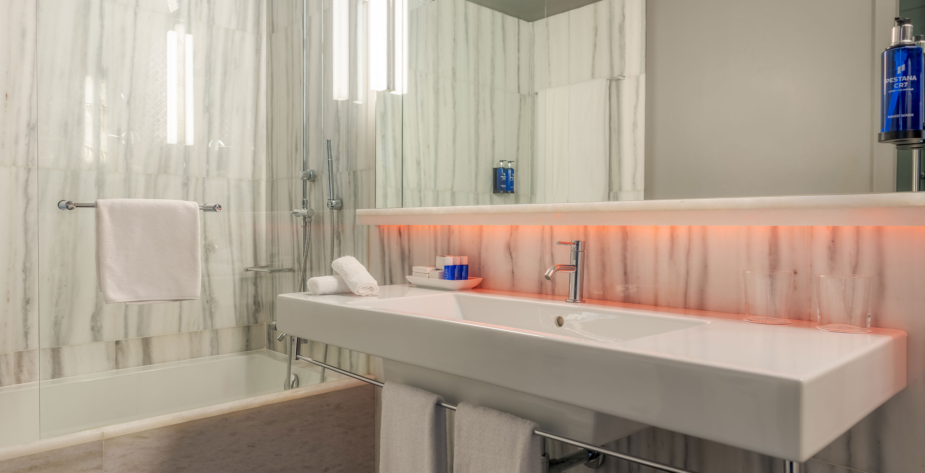 The CR7 Superior Corner Room at Pestana CR7 Lisboa features a bathroom with mirror, sink, and bathtub with shower