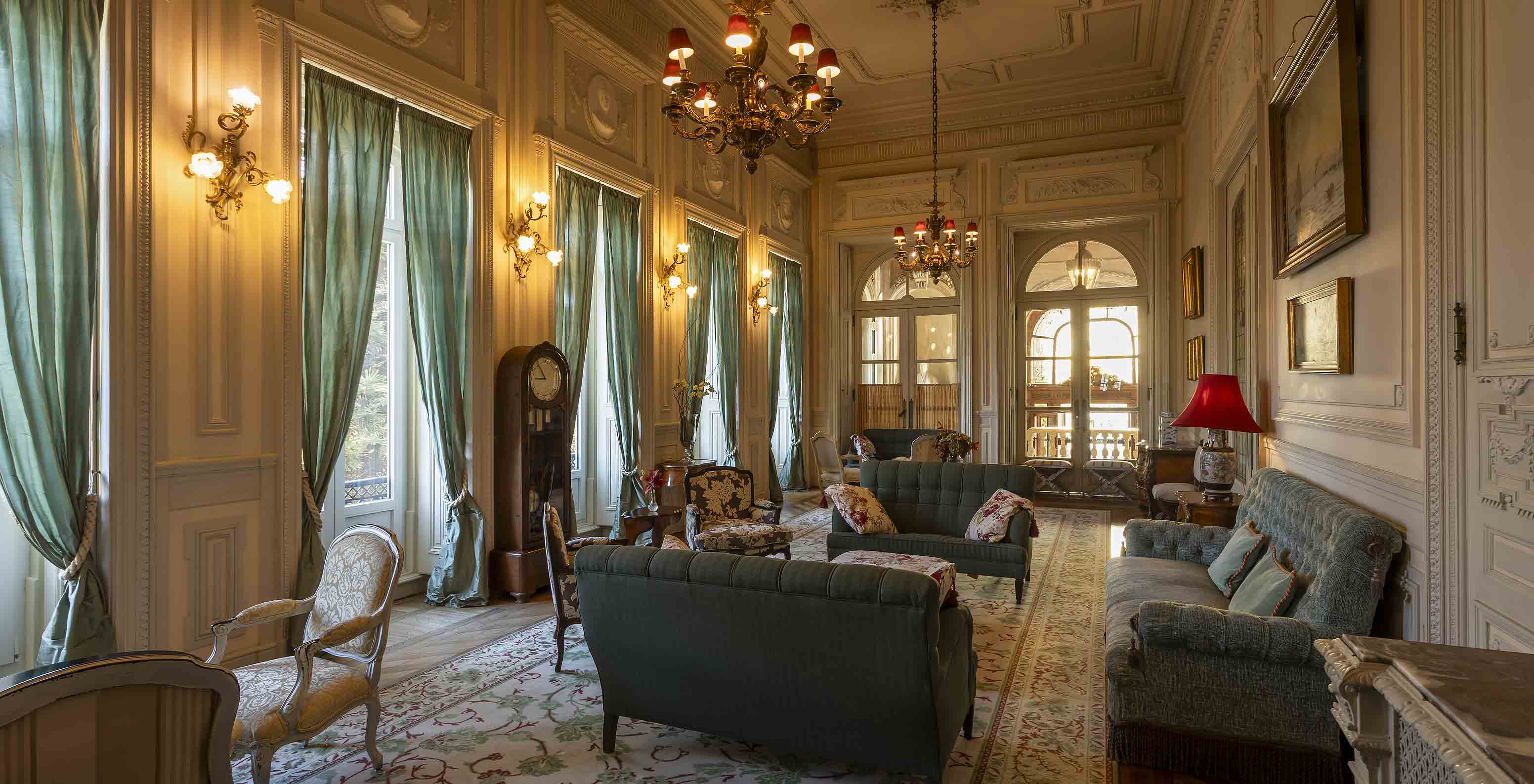 Pestana Palace Lisboa has a palace lounge with sofas, armchairs, and long green curtains covering the windows