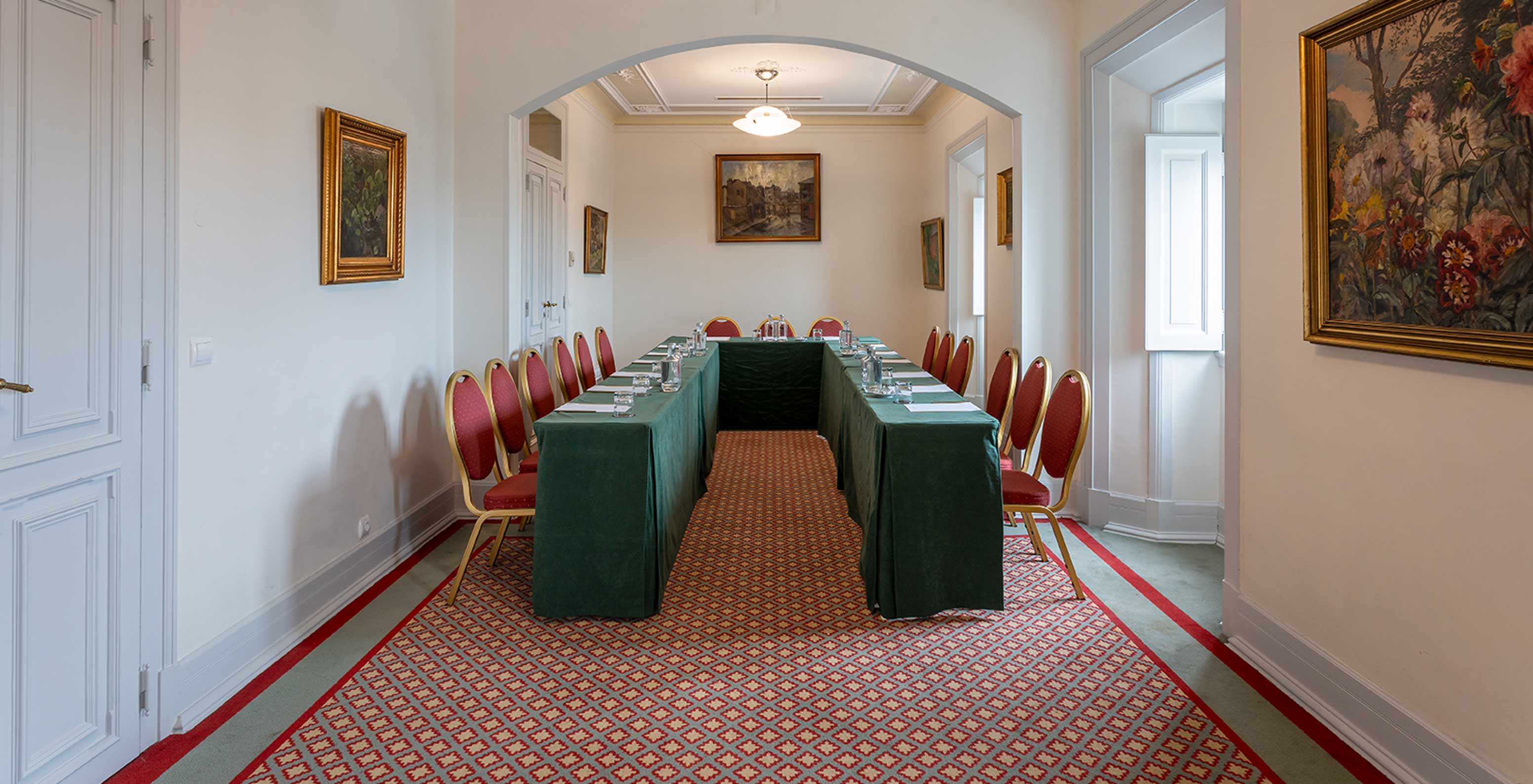 Pestana Palace Lisboa has a meeting room with a green U-shaped table and several red chairs