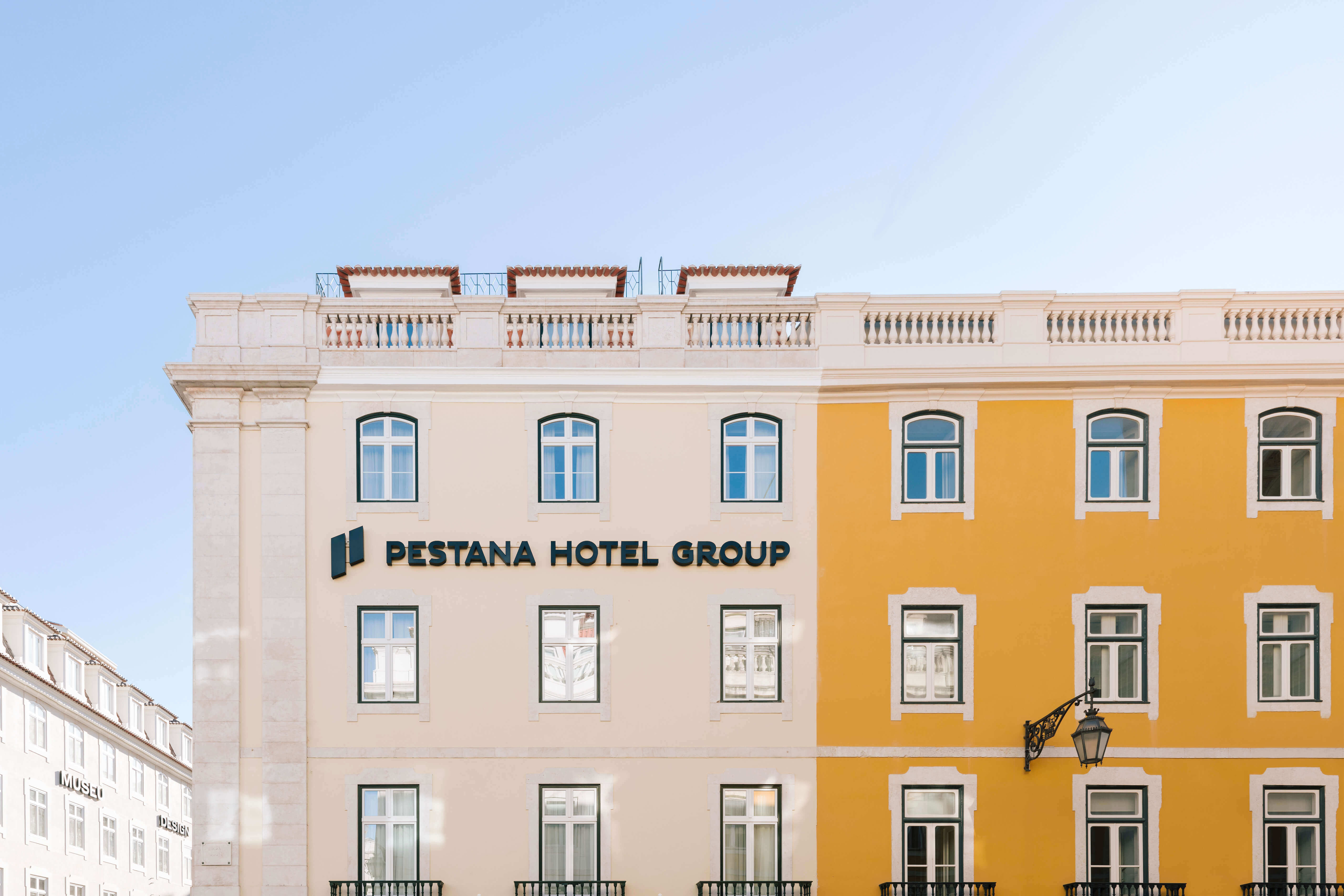 Side view of the white and orange building of Pestana Rua Augusta Lisboa with Pestana Hotel Group logo