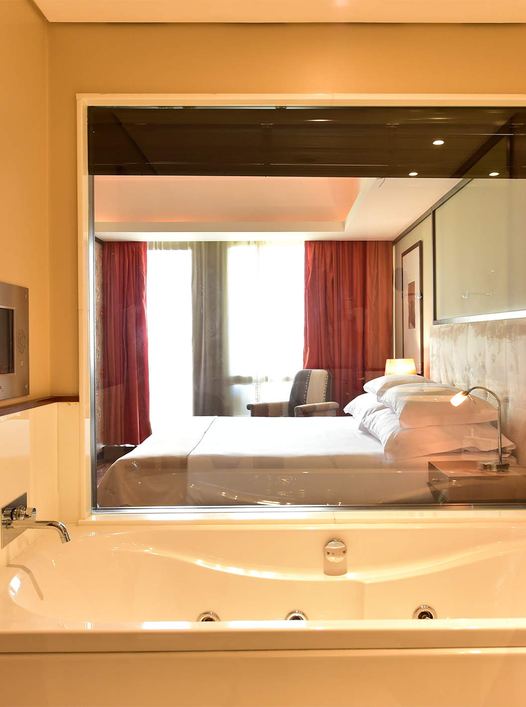 The Presidential Suite at Pestana Casino Park has a bathroom with a bathtub overlooking the double bed in the room