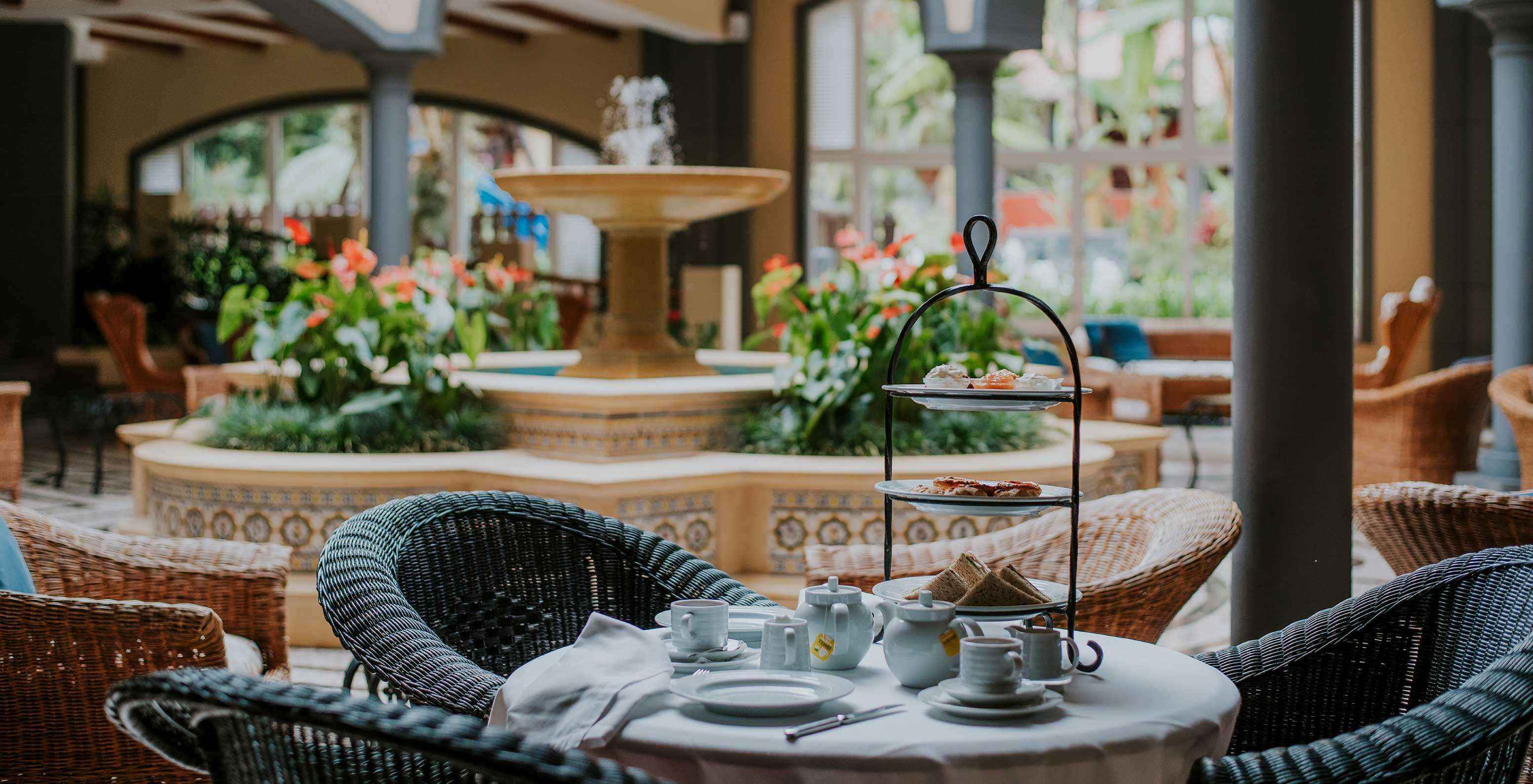 The bar A Fonte, at the Hotel de Charme in Madeira has a fountain with water and flowers and a table with chairs