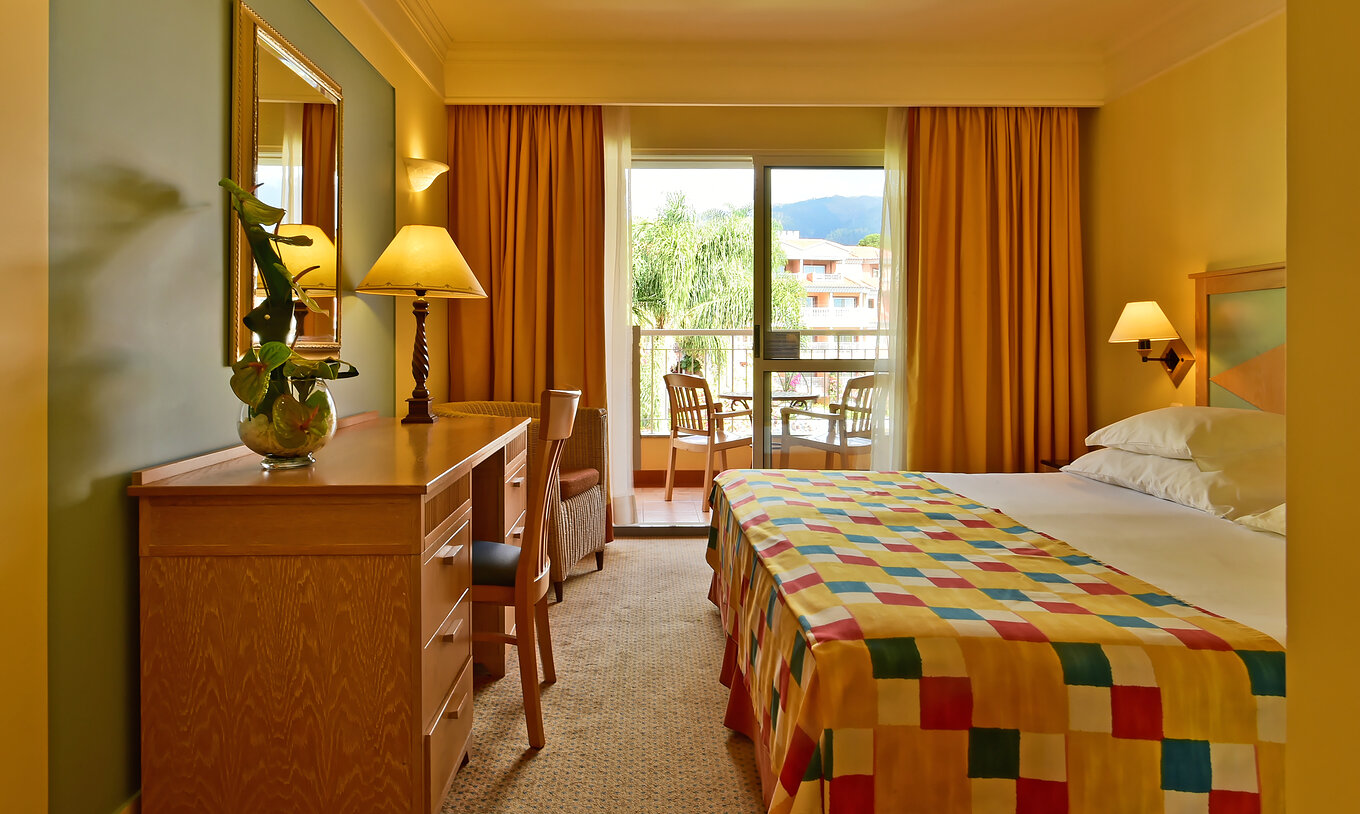 The Superior Room at Pestana Miramar has a double bed, a desk and a balcony with table and chairs