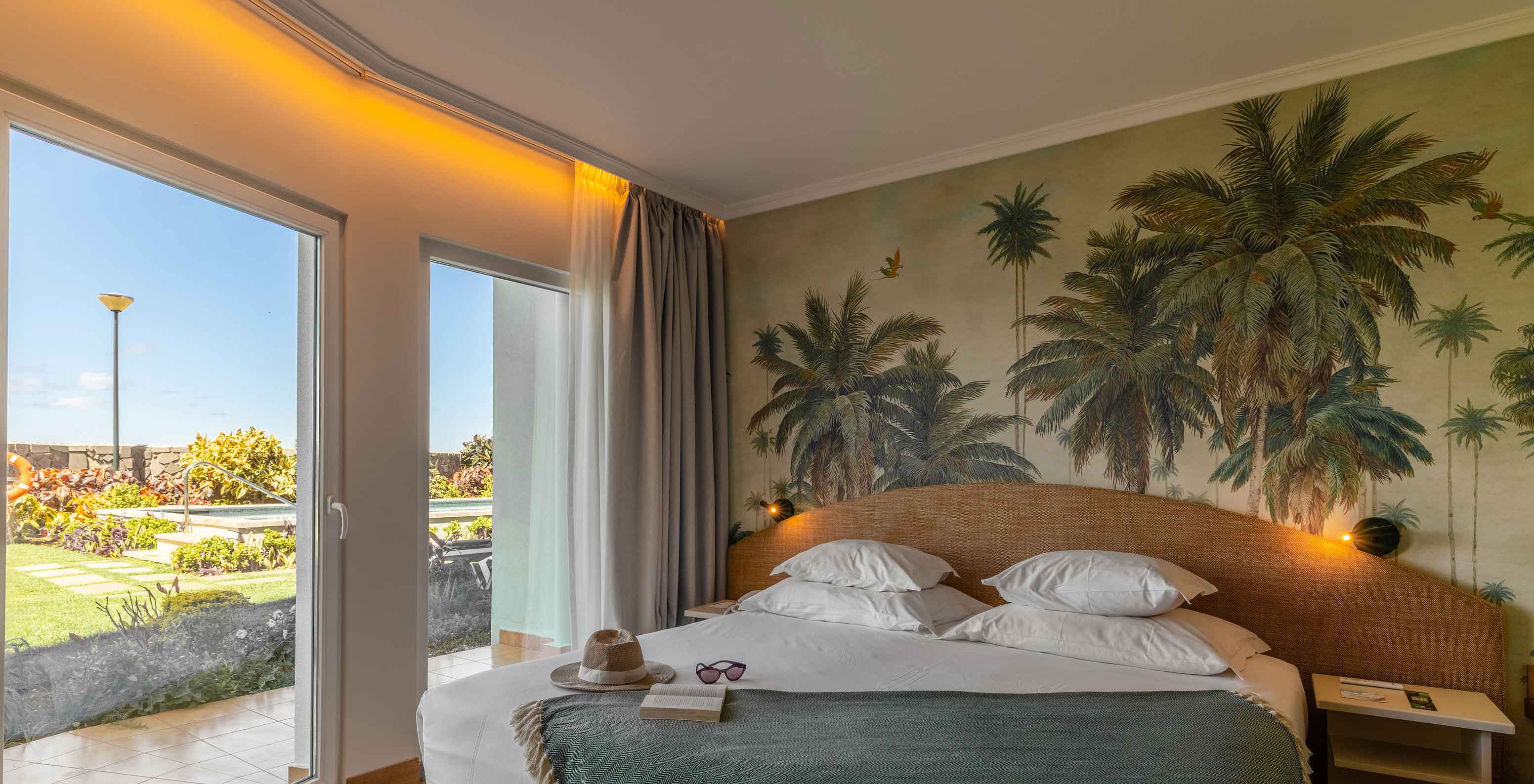 The Pestana Ocean Bay All Inclusive Junior Suite Sea View has a double bed with a green bedspread and wallpaper