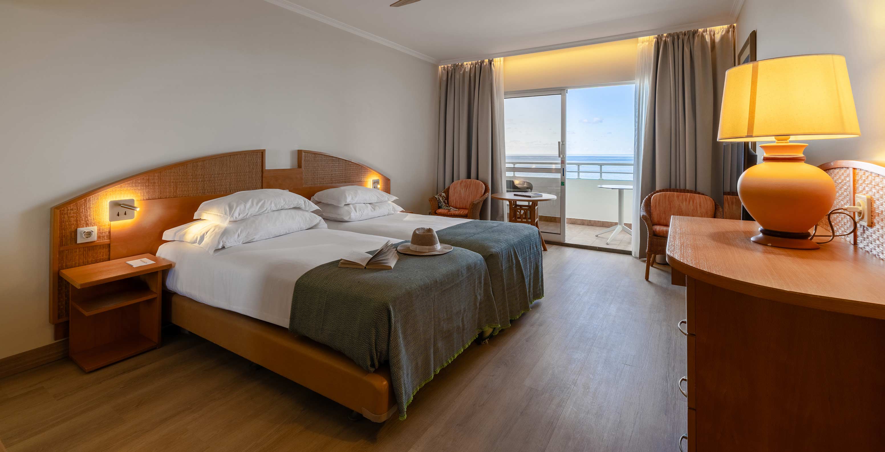 The Pestana Ocean Bay All Inclusive Classic Sea View has a double bed, a TV cabinet, two chairs, and a balcony with a view