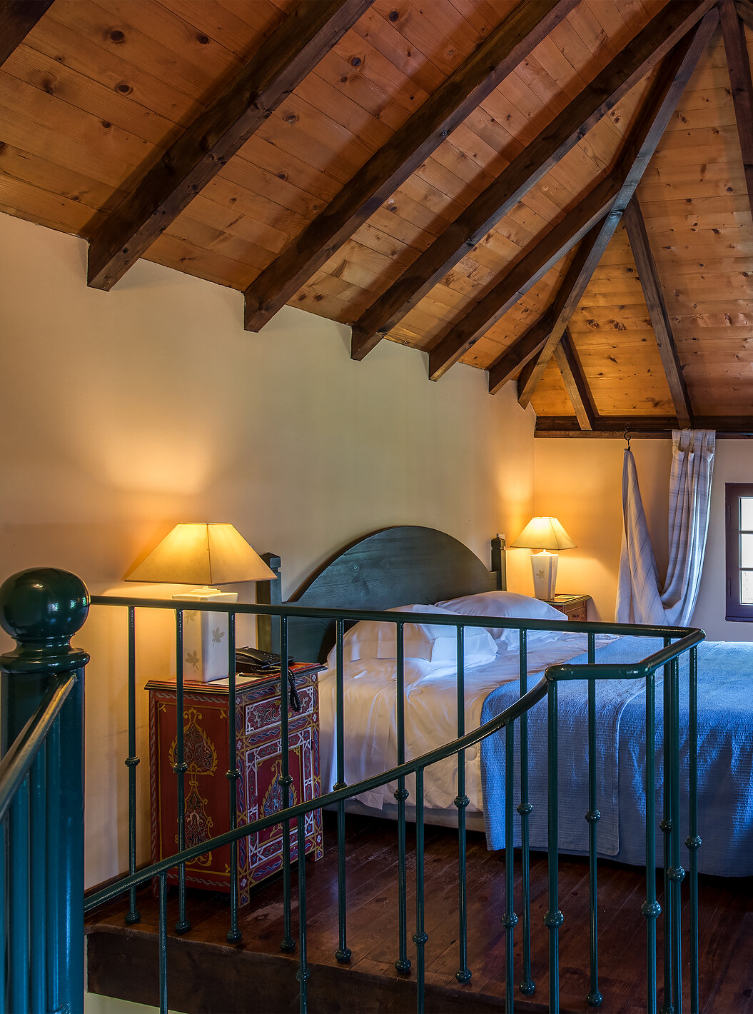 The Duplex Villas of Pestana Quinta do Arco have a double bed with wooden ceiling, nightstands, and wooden dresser