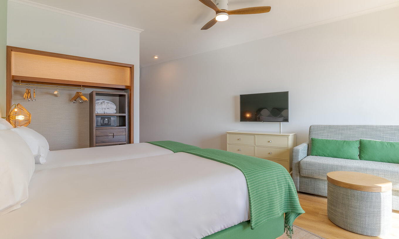 The Classic Sea View room at Pestana Vila Lido Madeira features a wall-mounted television, a wardrobe with safe, and two beds