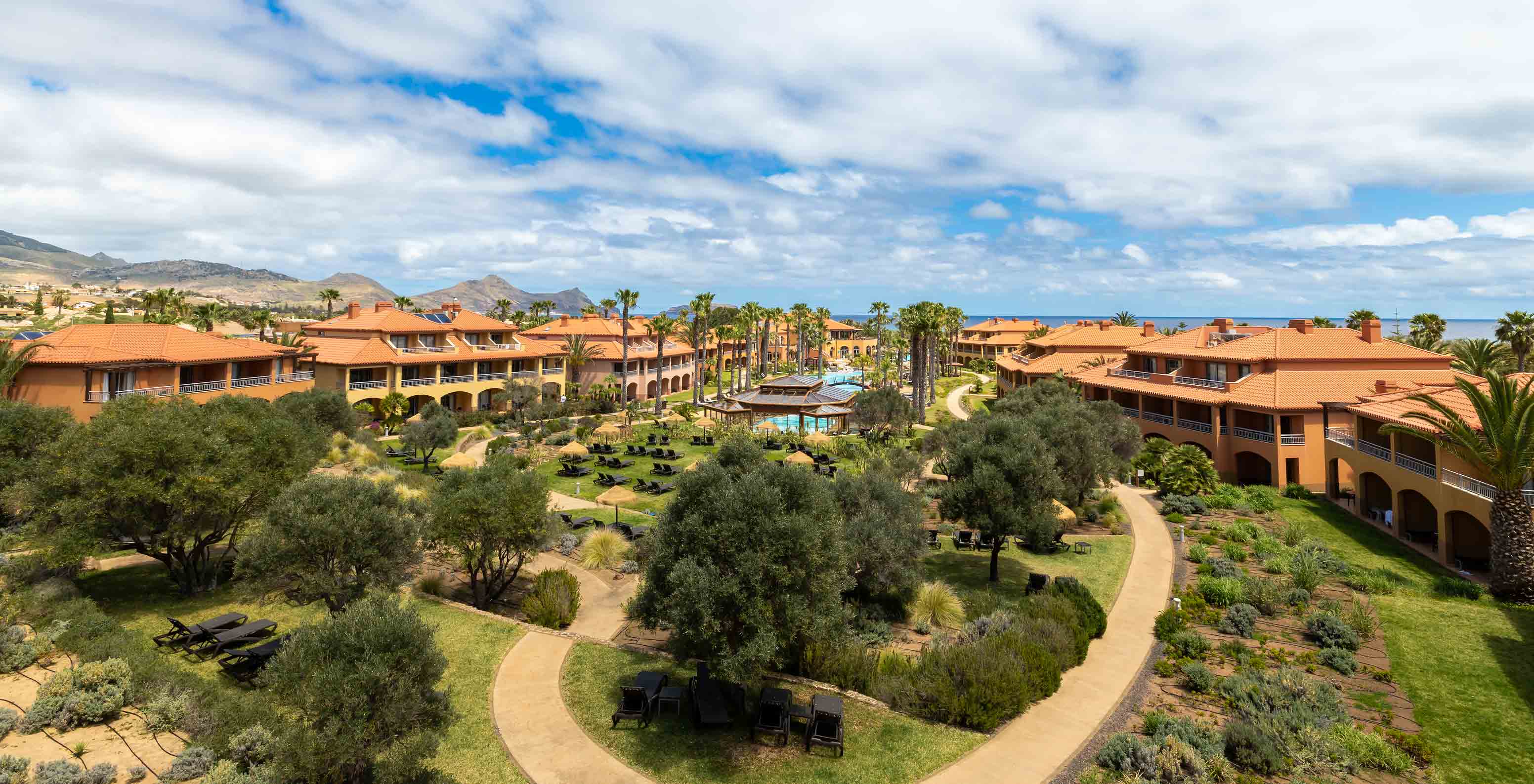 Gardens of Pestana Porto Santo All Inclusive with grass, tropical palm trees, sun loungers, and villas around