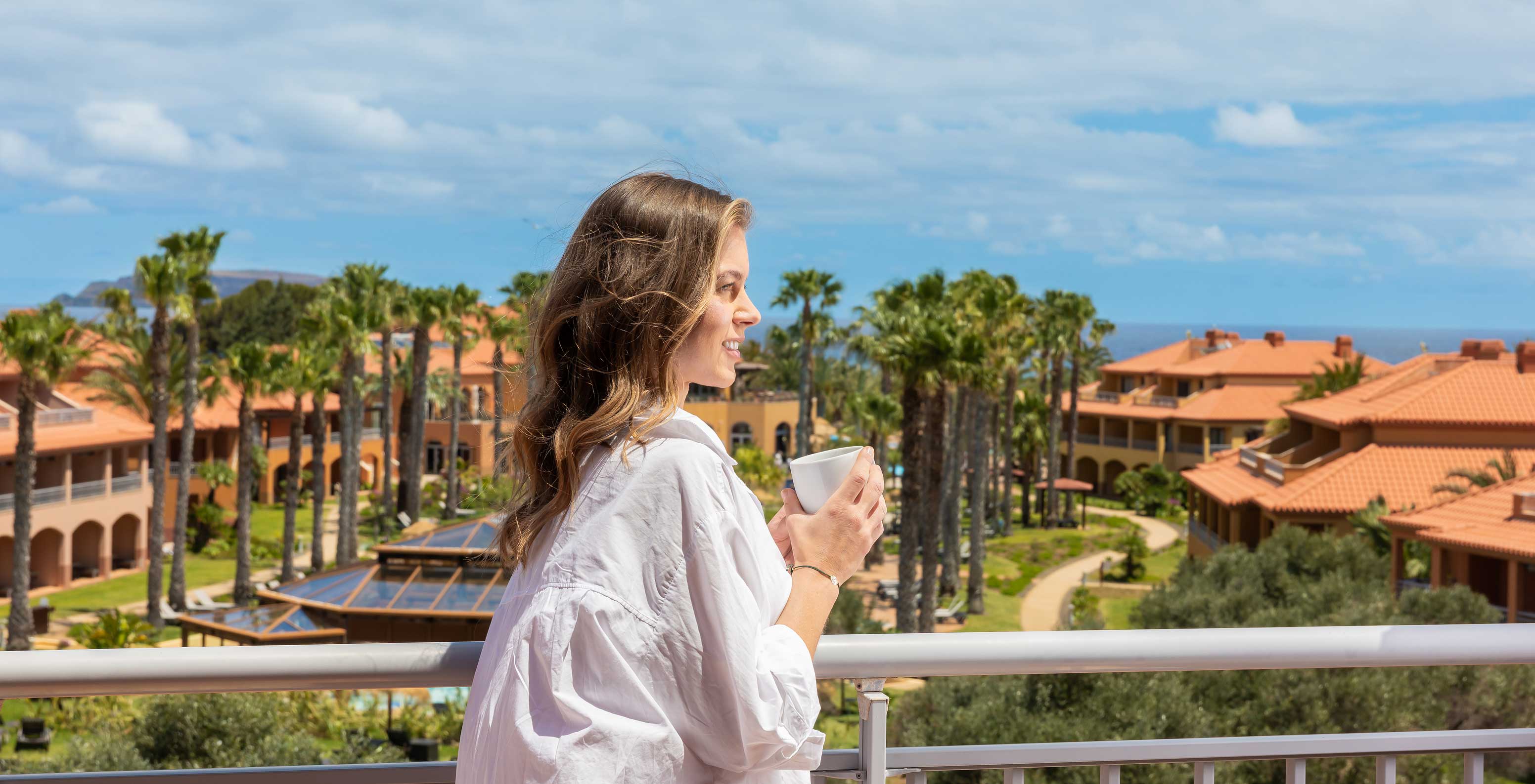 Guest enjoying the view of the garden at Pestana Porto Santo All Inclusive, with several villas and vegetation