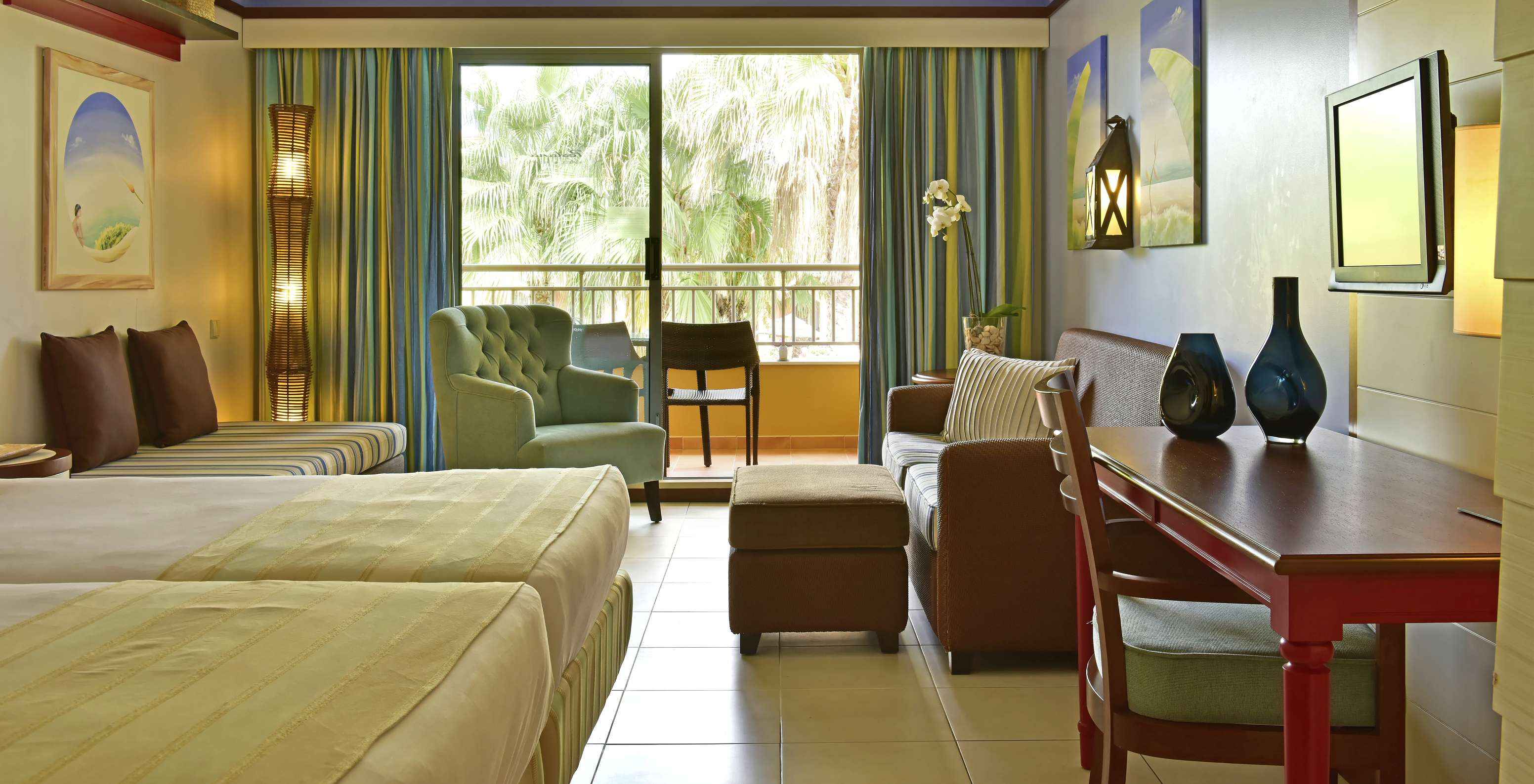The Family Double of Pestana Porto Santo All Inclusive has two beds, a television, sofas, and a balcony with garden view