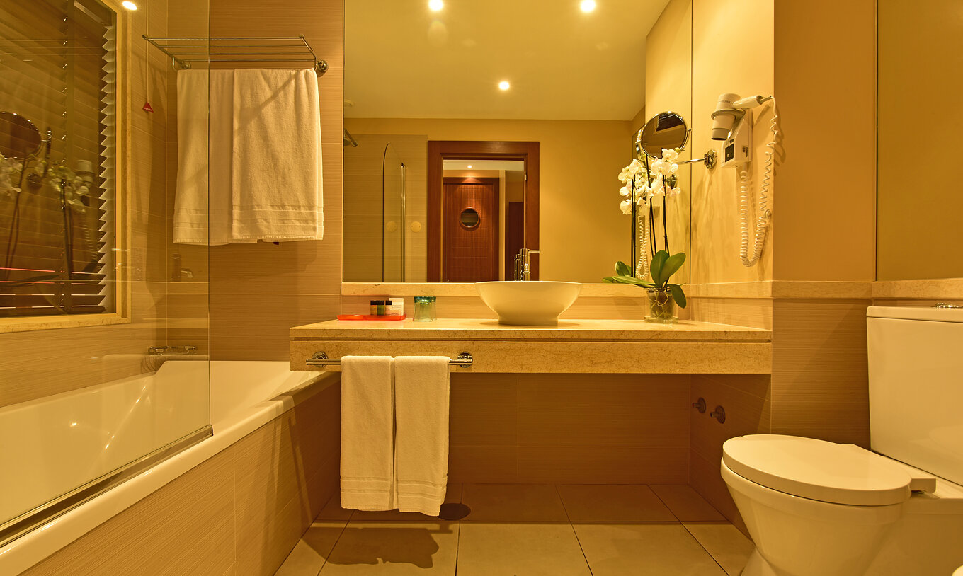 The Pool View Double of Pestana Porto Santo All Inclusive has a bathroom with sink, mirror, toilet, and towels