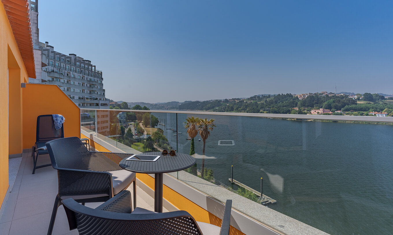 The Suite at Pestana Douro Riverside has a balcony with a view of the Douro River, with table, chairs, and loungers