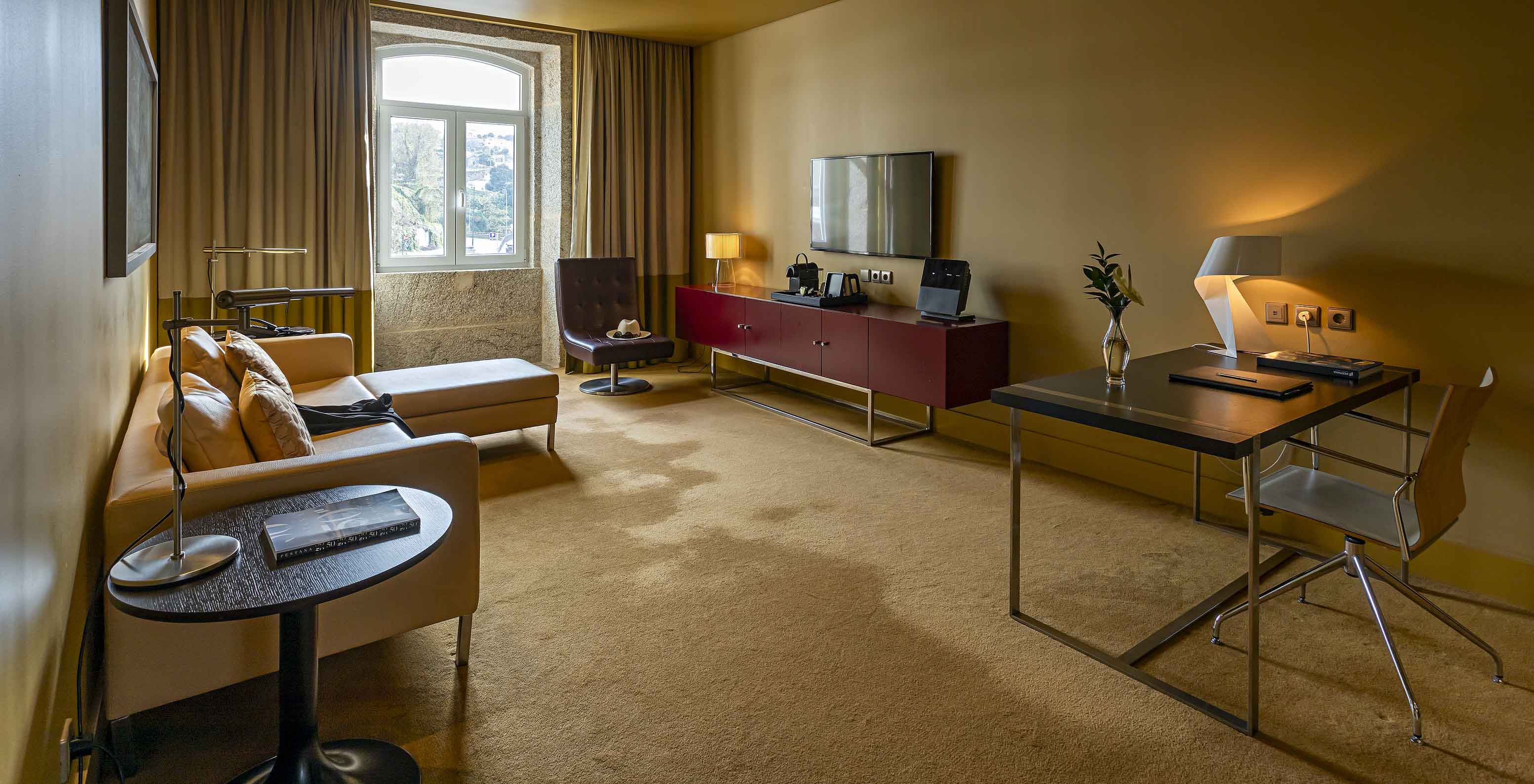 The Junior Suite has a living room with a chaise-longue sofa, a desk, and a TV
