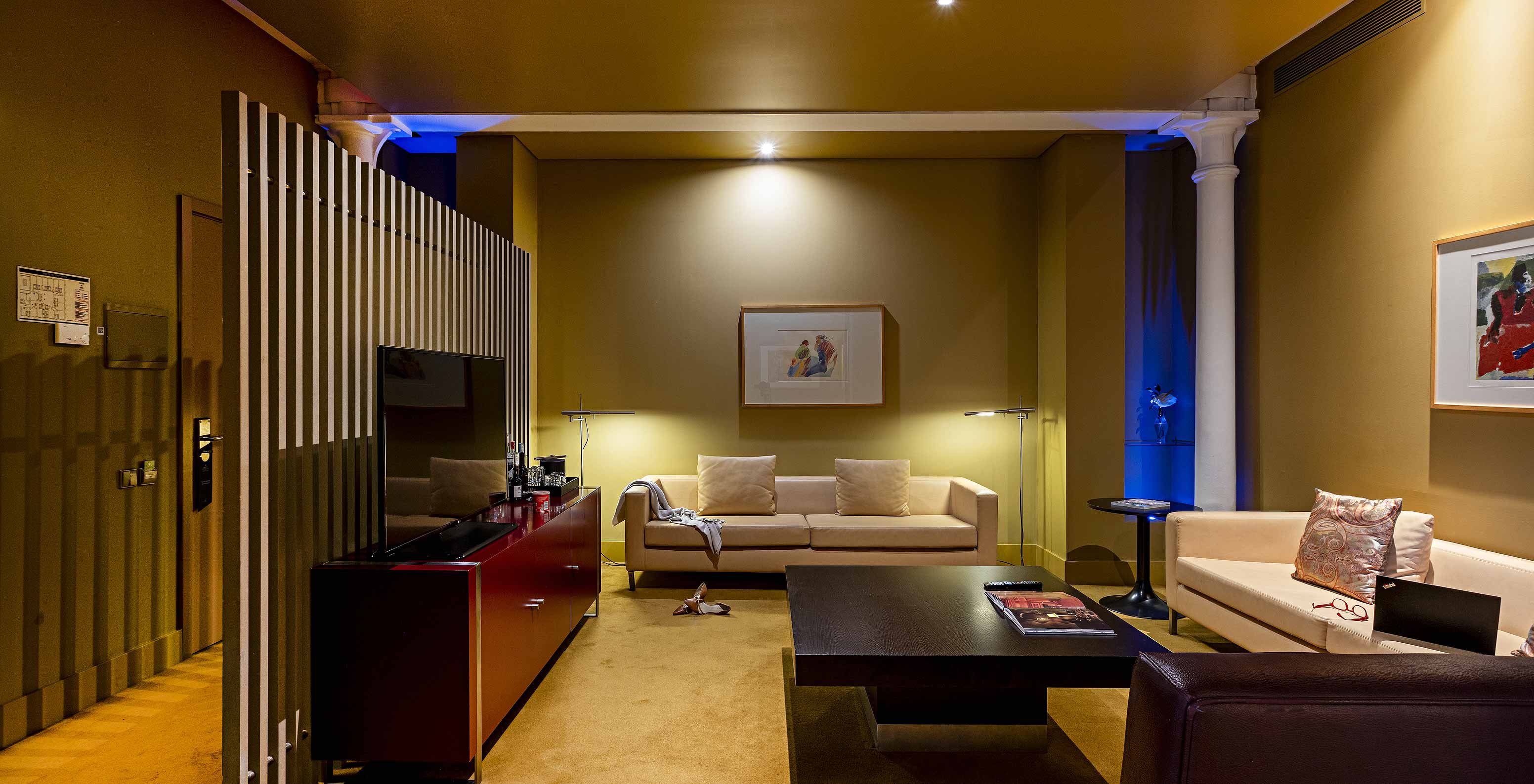 The Suite Balcony has a living room with three sofas, a coffee table, and a TV stand
