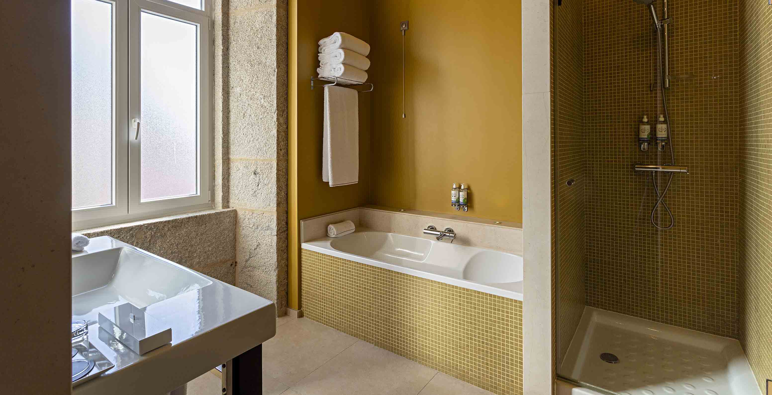 The Suite Nasoni has a bathroom with yellow tiles, a bathtub, and shower area
