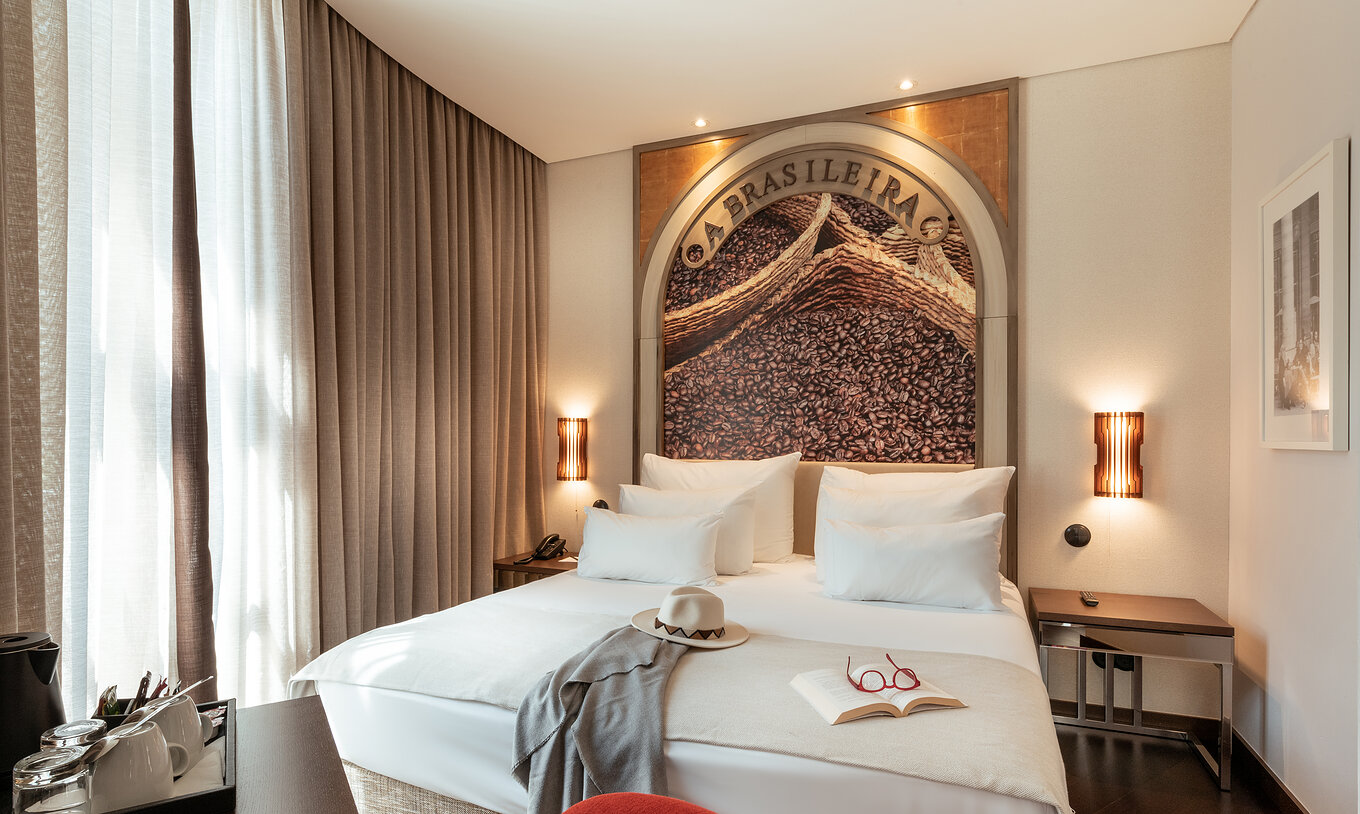The Deluxe do Pestana Porto - A Brasileira has a double bed with a themed mural on the headboard