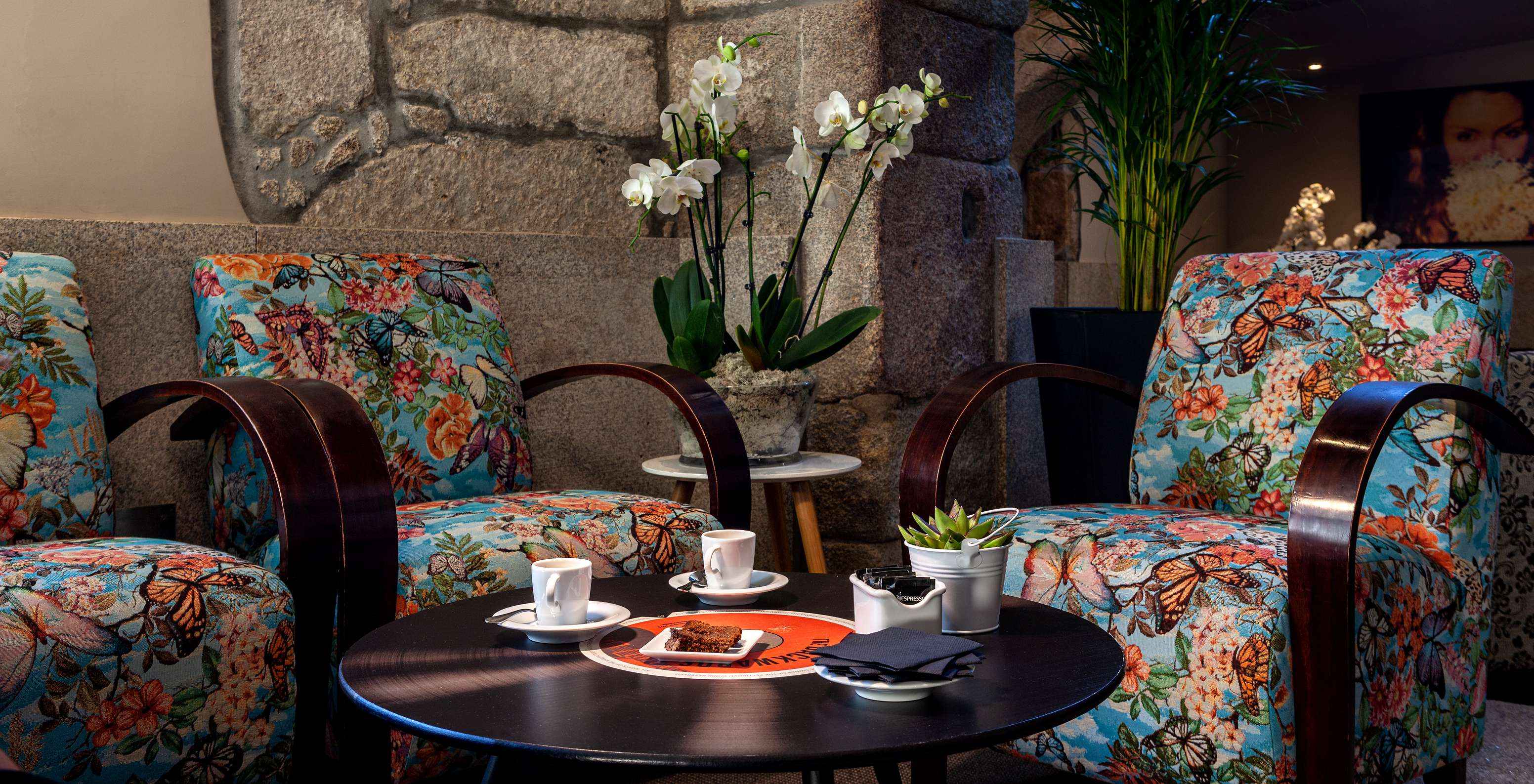 Seating area with floral sofas, coffee, and brownies at Pestana Vintage Porto, a hotel at Praça da Ribeira