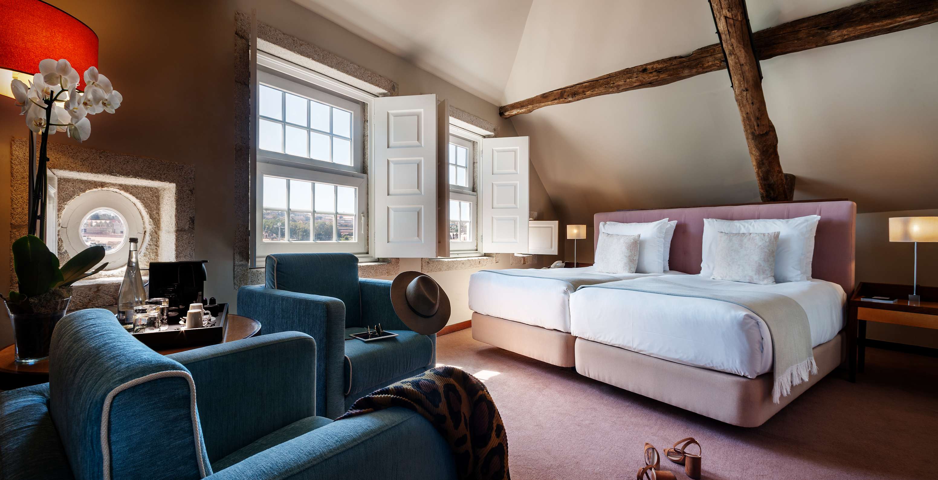 The Plaza room at Pestana Vintage Porto has two beds, two armchairs, a wooden beam on the ceiling and two large windows
