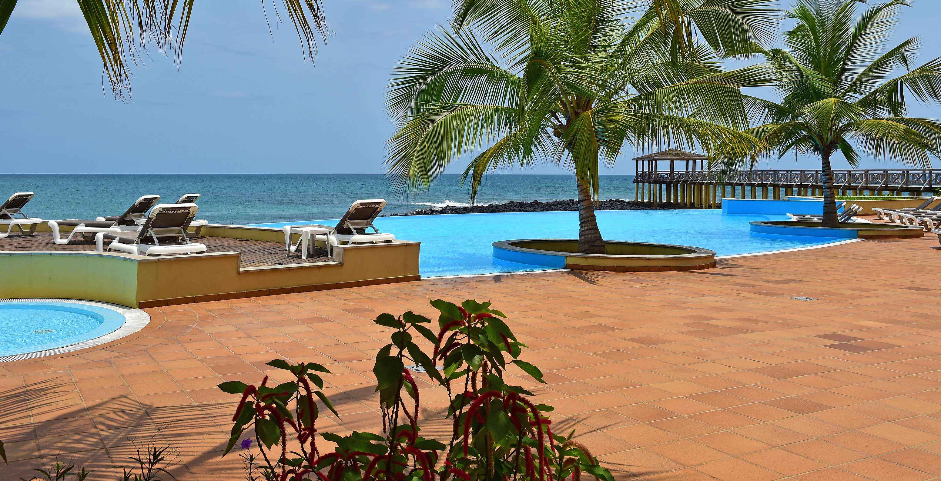 Pool area with loungers and palm trees creating a tropical atmosphere with the pier in the background