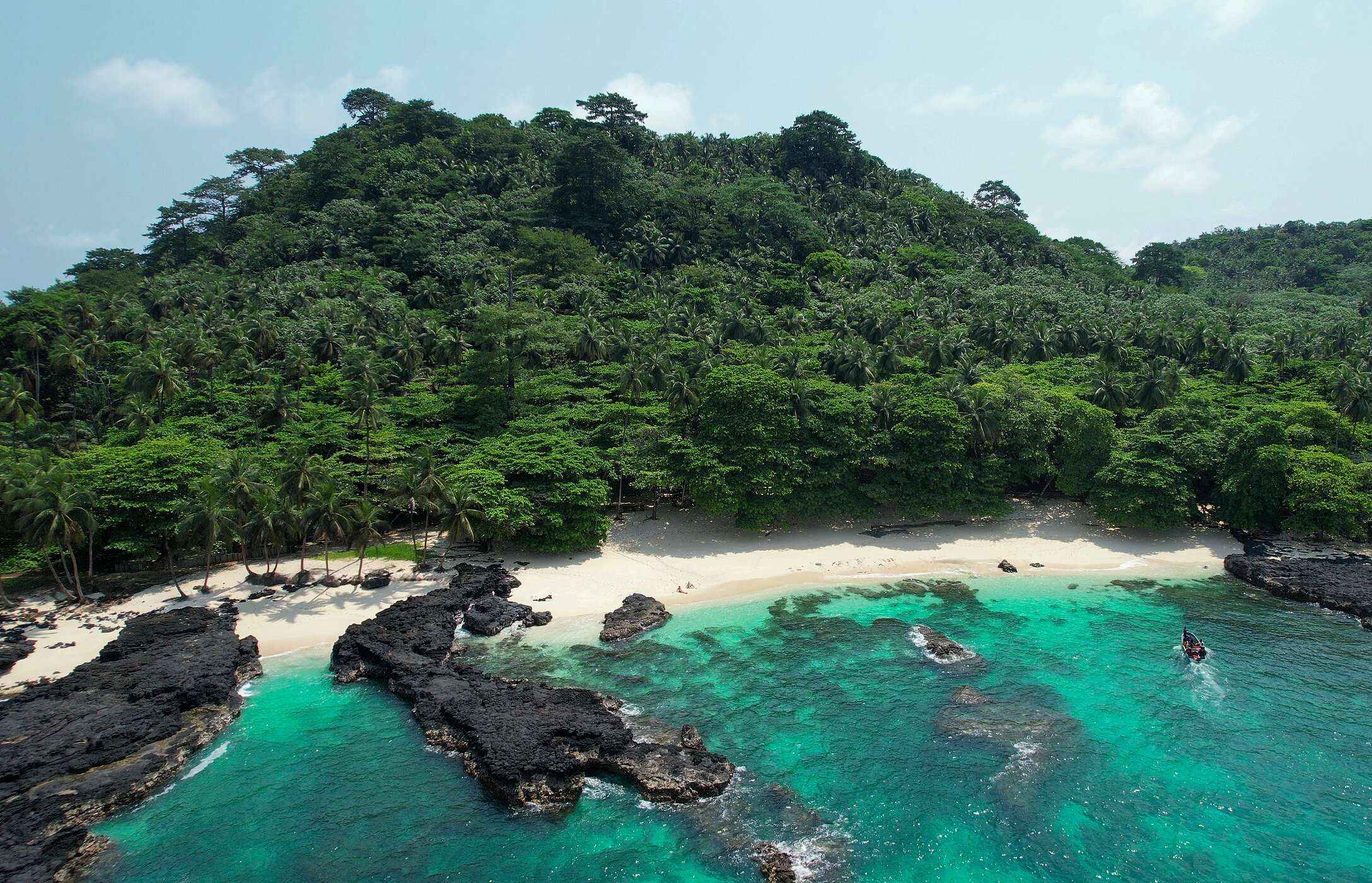 Praia Café, on the island of São Tomé, deserted, with rocks both on the beach and in the sea, and a wall of vegetation