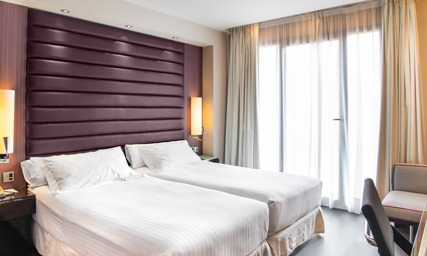 Standard room at Pestana Arena Barcelona has two single beds with bedside table, an armchair and a window