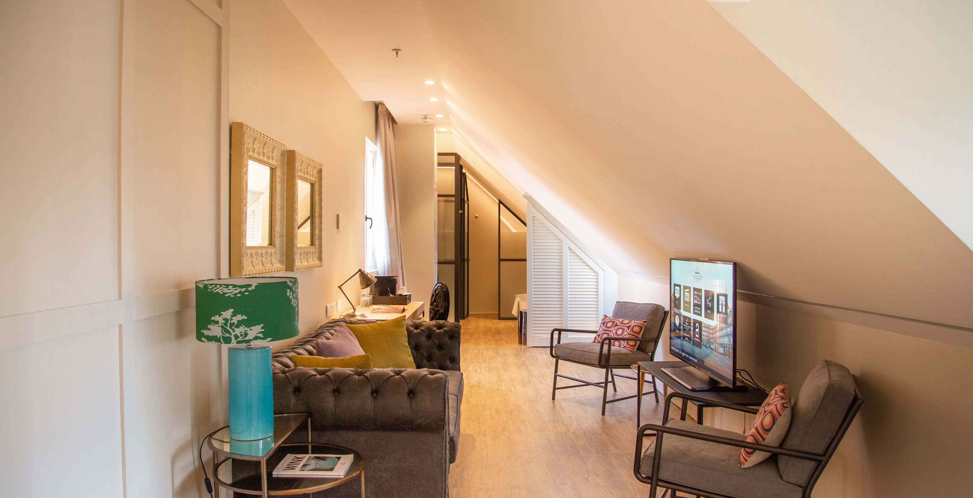 The Suite Plaza Mayor at Pestana Collection Plaza Mayor has a living room with sofa, chairs, TV and paintings on the wall