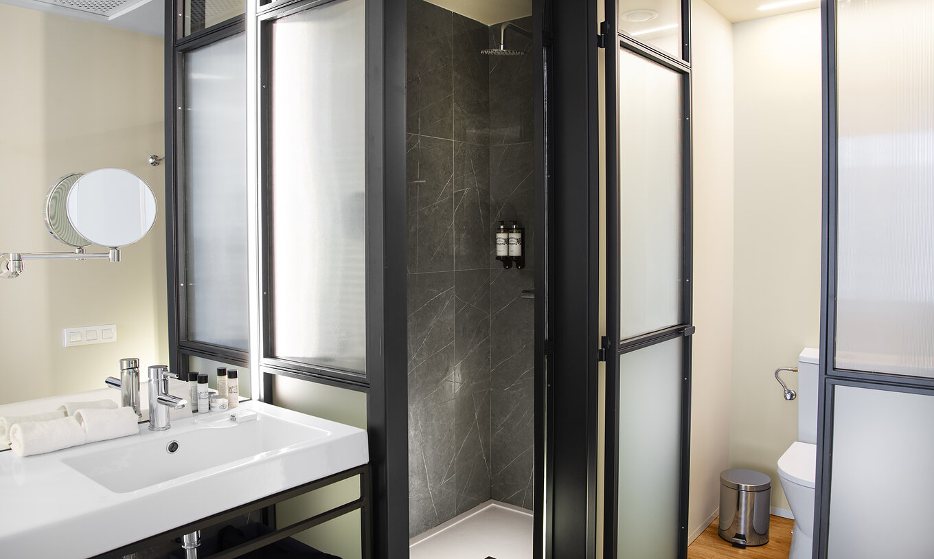 The Superior Plaza Mayor at Pestana Plaza Mayor Madrid has a bathroom with sink with mirror, shower and towels