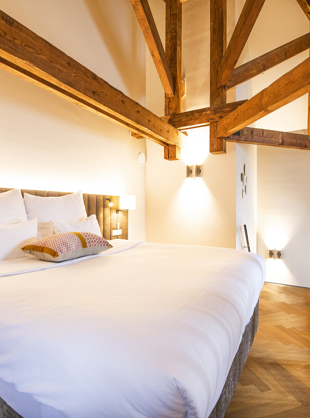 Clock Tower Suite at Pestana Amsterdam Riverside has a double bed, with lamp, and wooden beams on the walls