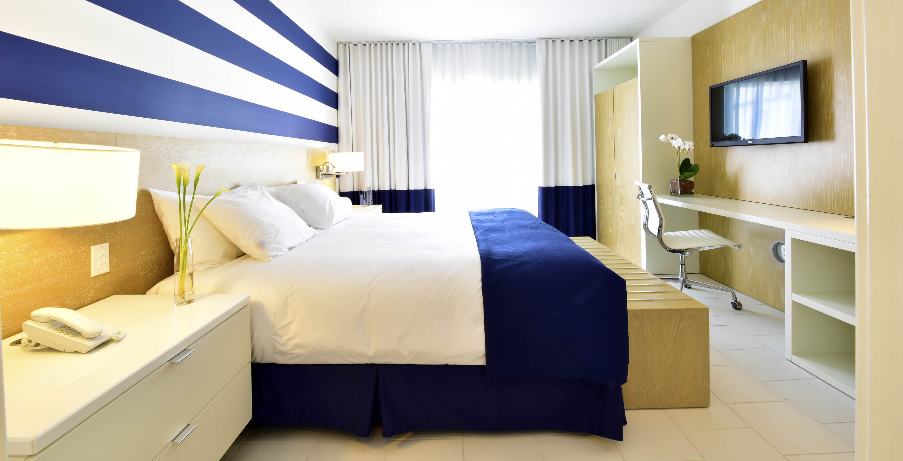 The Suite King with Balcony at Pestana Miami is modern with large bed and blue-white decor