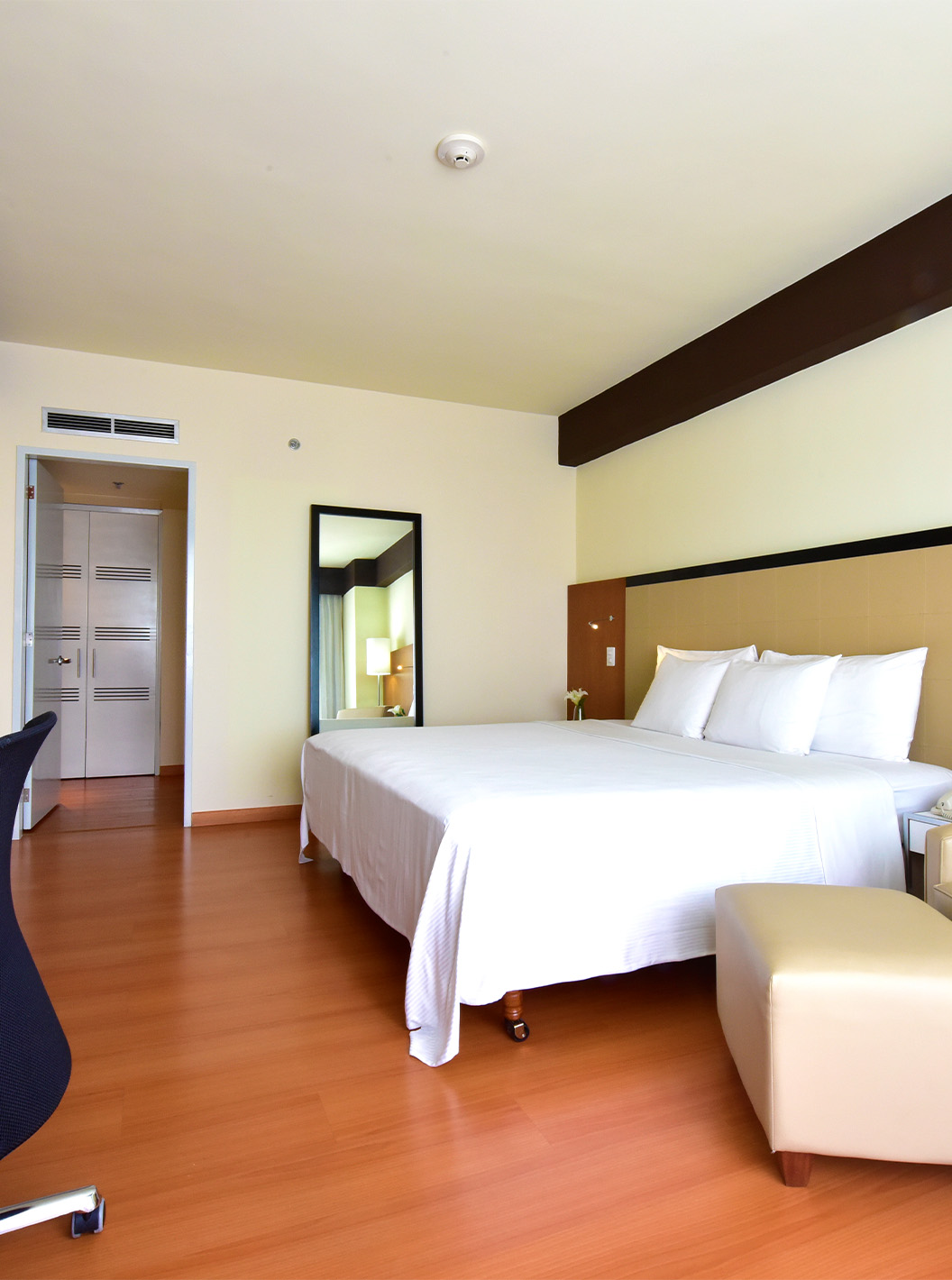 The Executive King Room at Pestana Caracas has a double bed, a large mirror, a desk, and an armchair