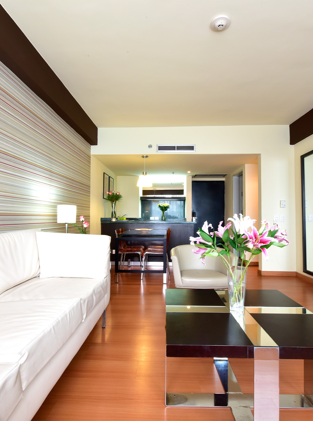The Twin Junior Suite at Pestana Caracas has a living room with a two-seater white sofa, a TV, and a side table