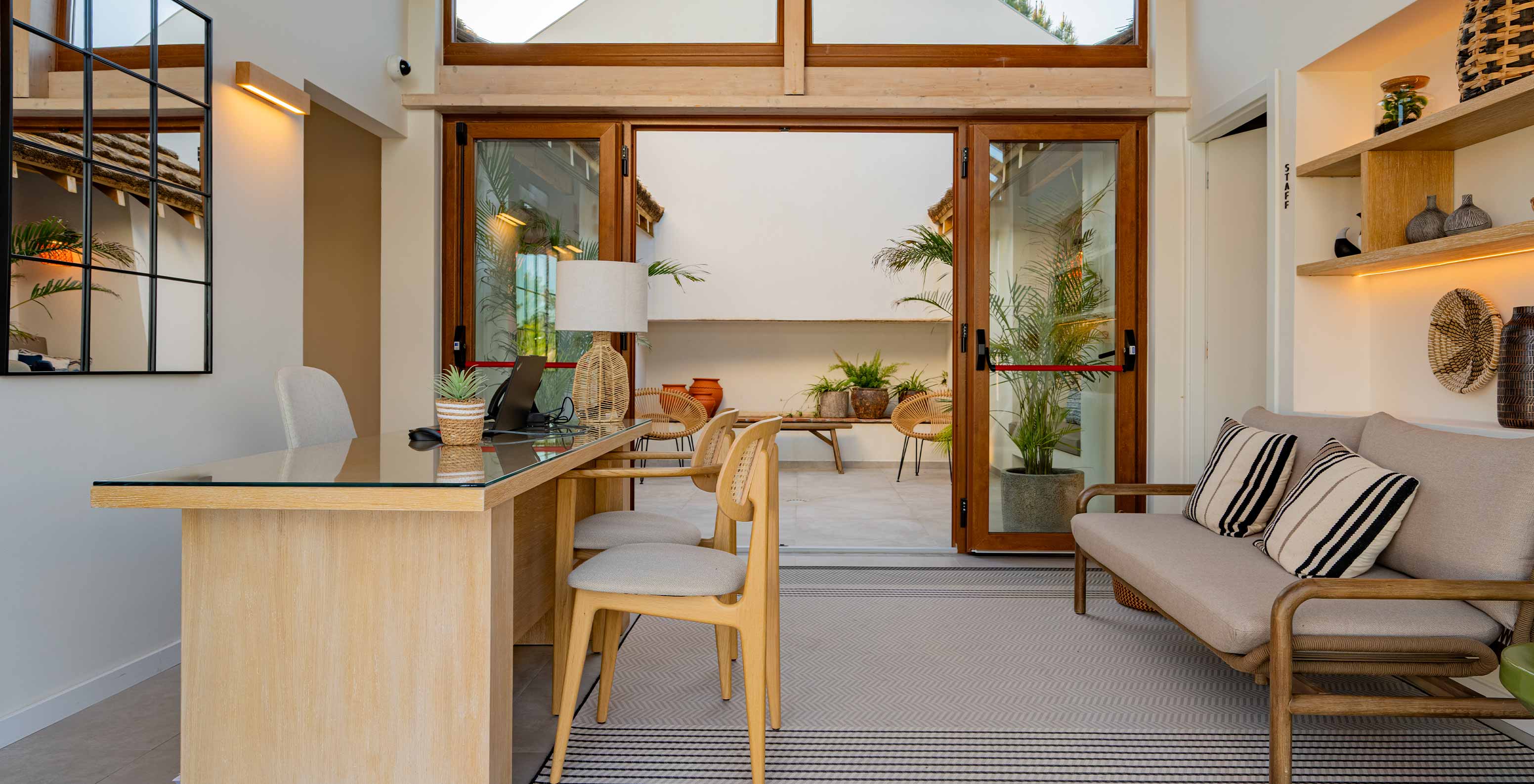 Recepción moderna y acogedora con un sofá y puertas dobles de vidrio, en Pestana Comporta Village Residences